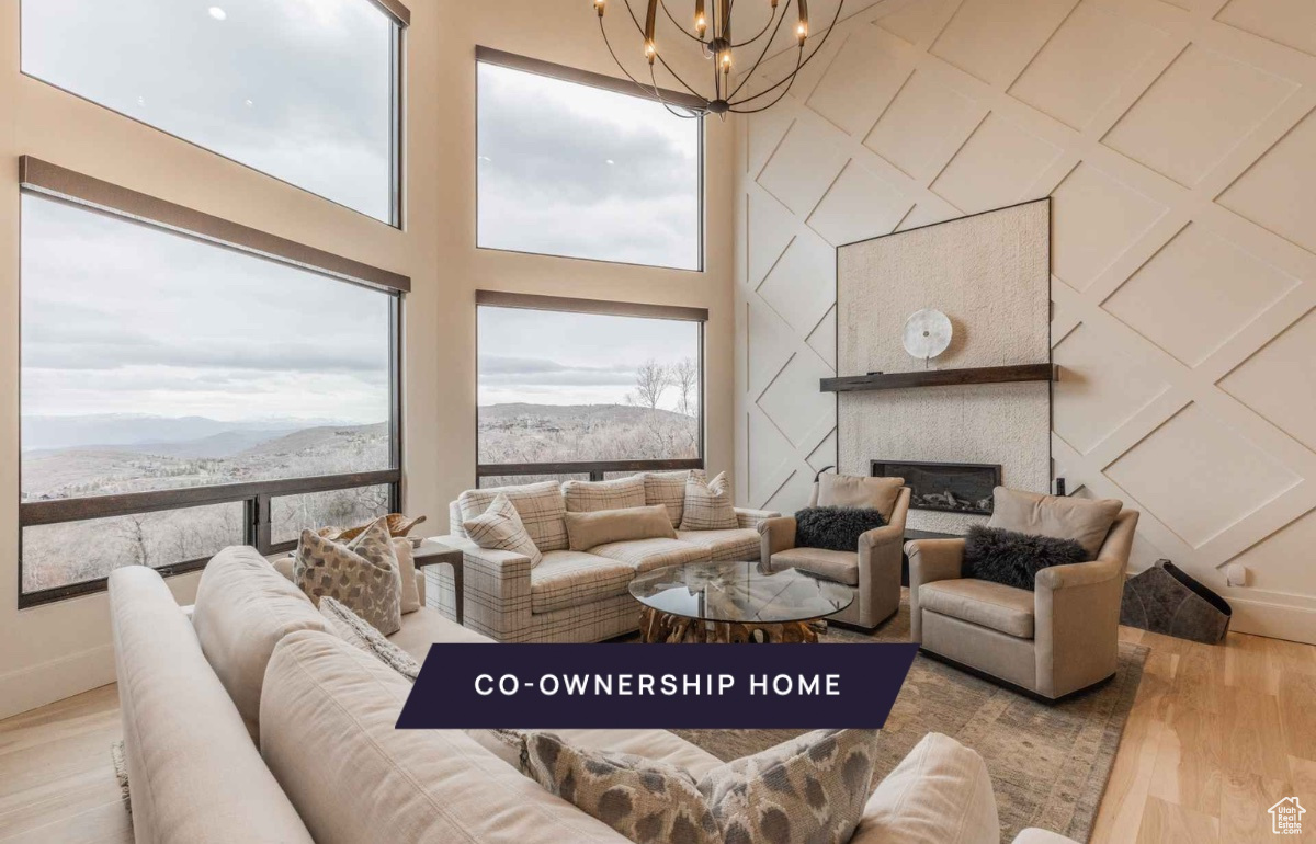 Living room with a towering ceiling, a mountain view, light hardwood / wood-style flooring, and a notable chandelier