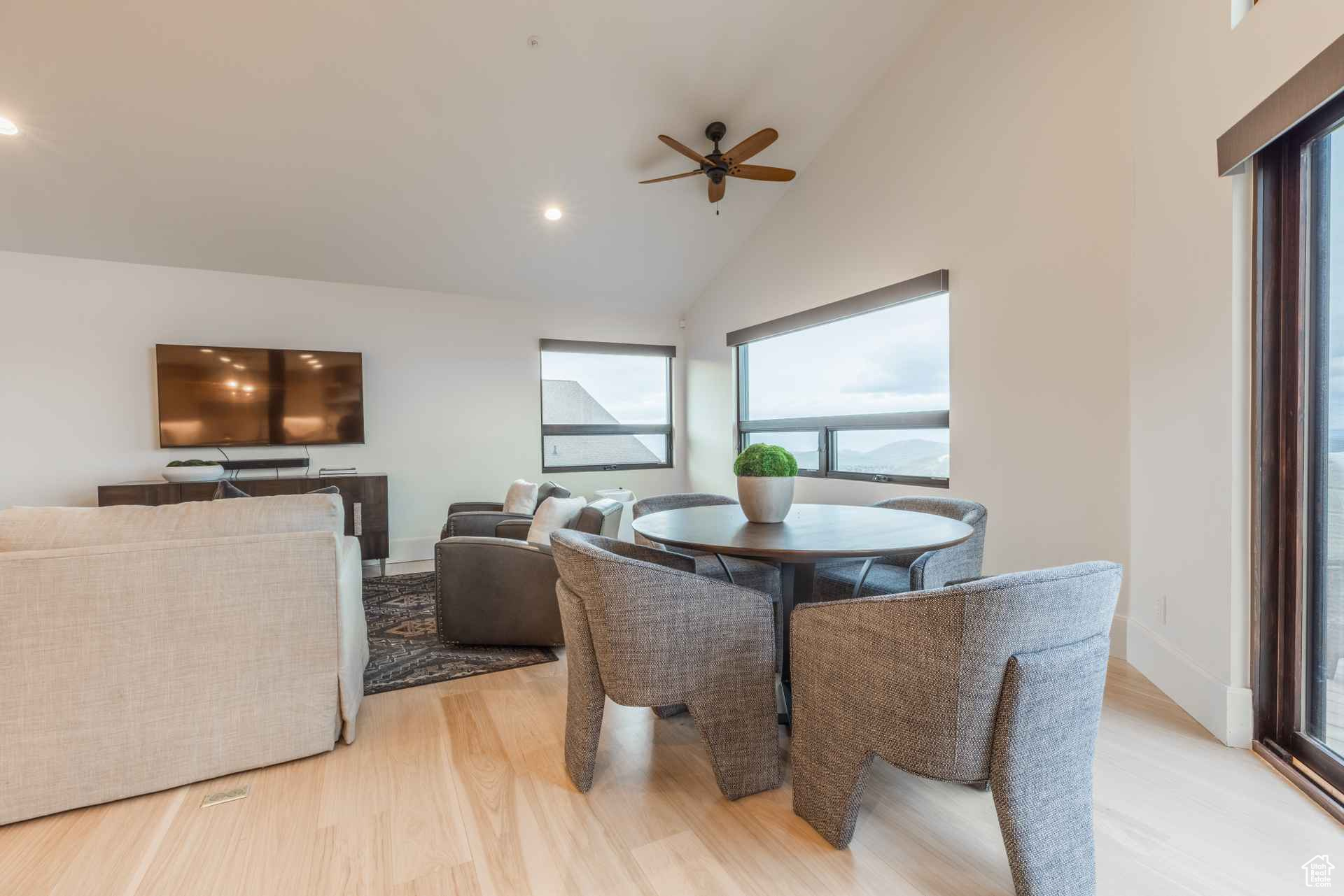 Dining space with high vaulted ceiling and light hardwood / wood-style flooring