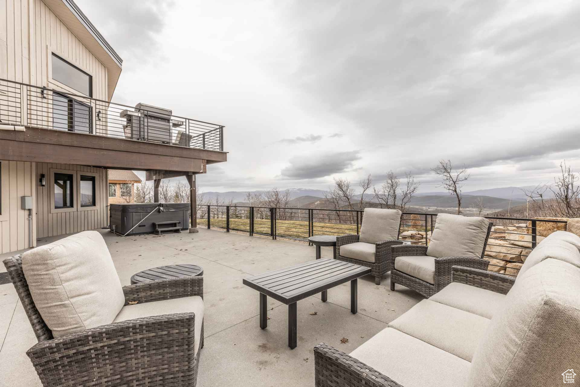 View of patio with a hot tub, a balcony, an outdoor hangout area, and a mountain view