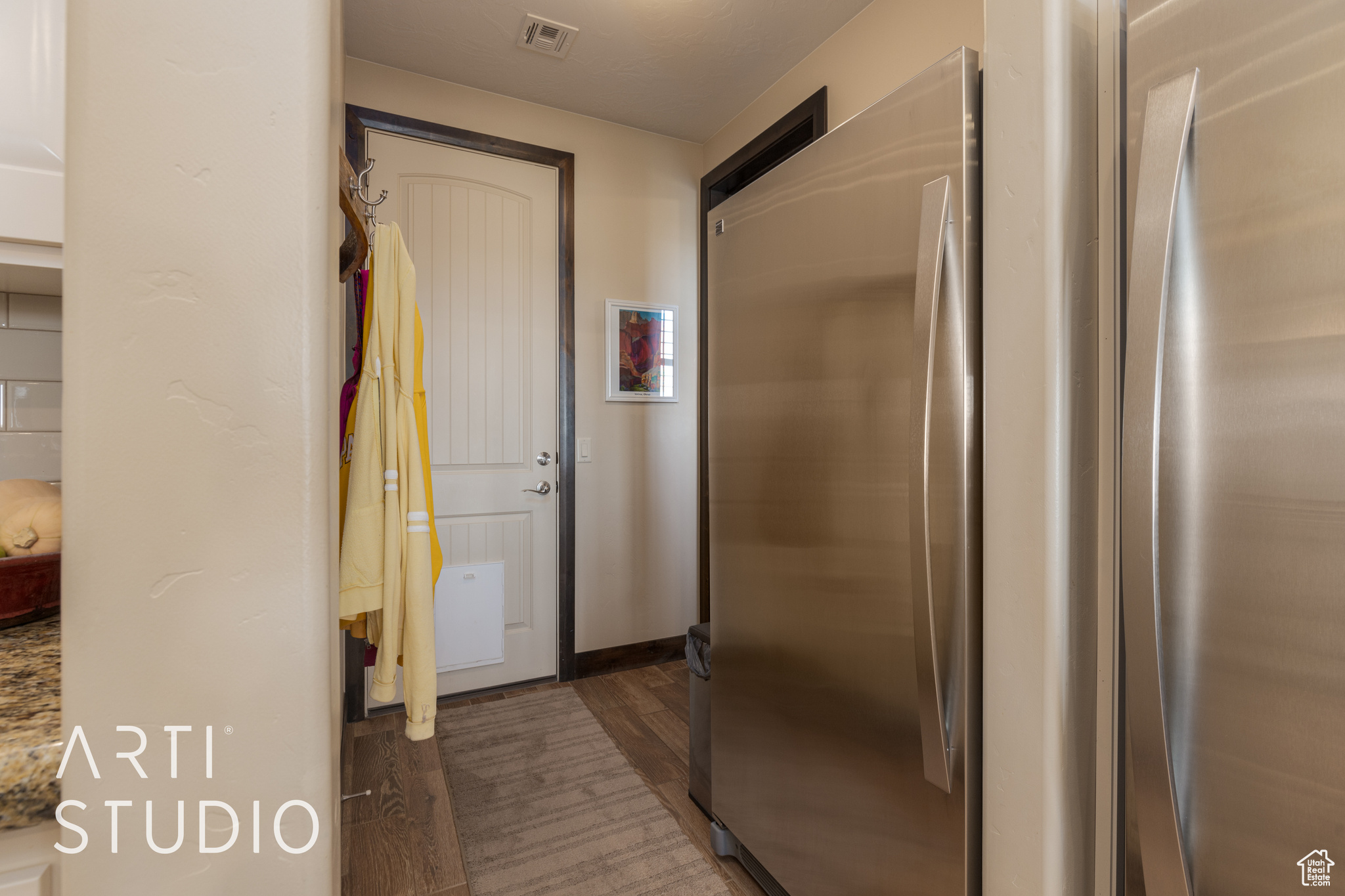 Hallway to pantry. Full refrigerator and full freezer with wood look tile flooring