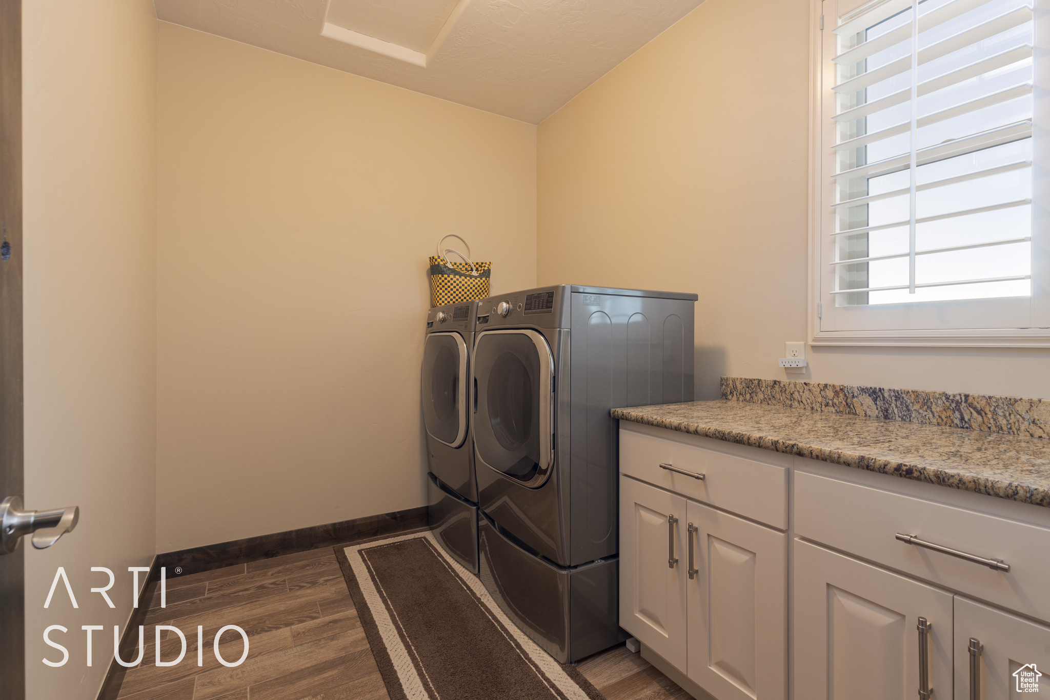 Laundry room with wood look tile flooring, cabinets, granite countertop and washer and dryer