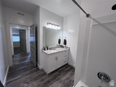 Bathroom with vanity, hardwood / wood-style flooring, and shower / bathtub combination