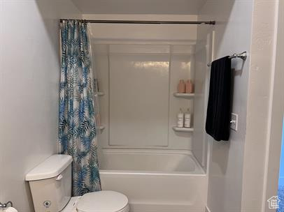 Bathroom featuring shower / bathtub combination with curtain and toilet