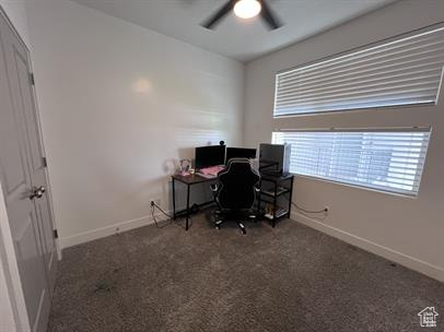 Office area featuring ceiling fan and dark carpet