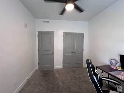 Office area with ceiling fan and dark carpet