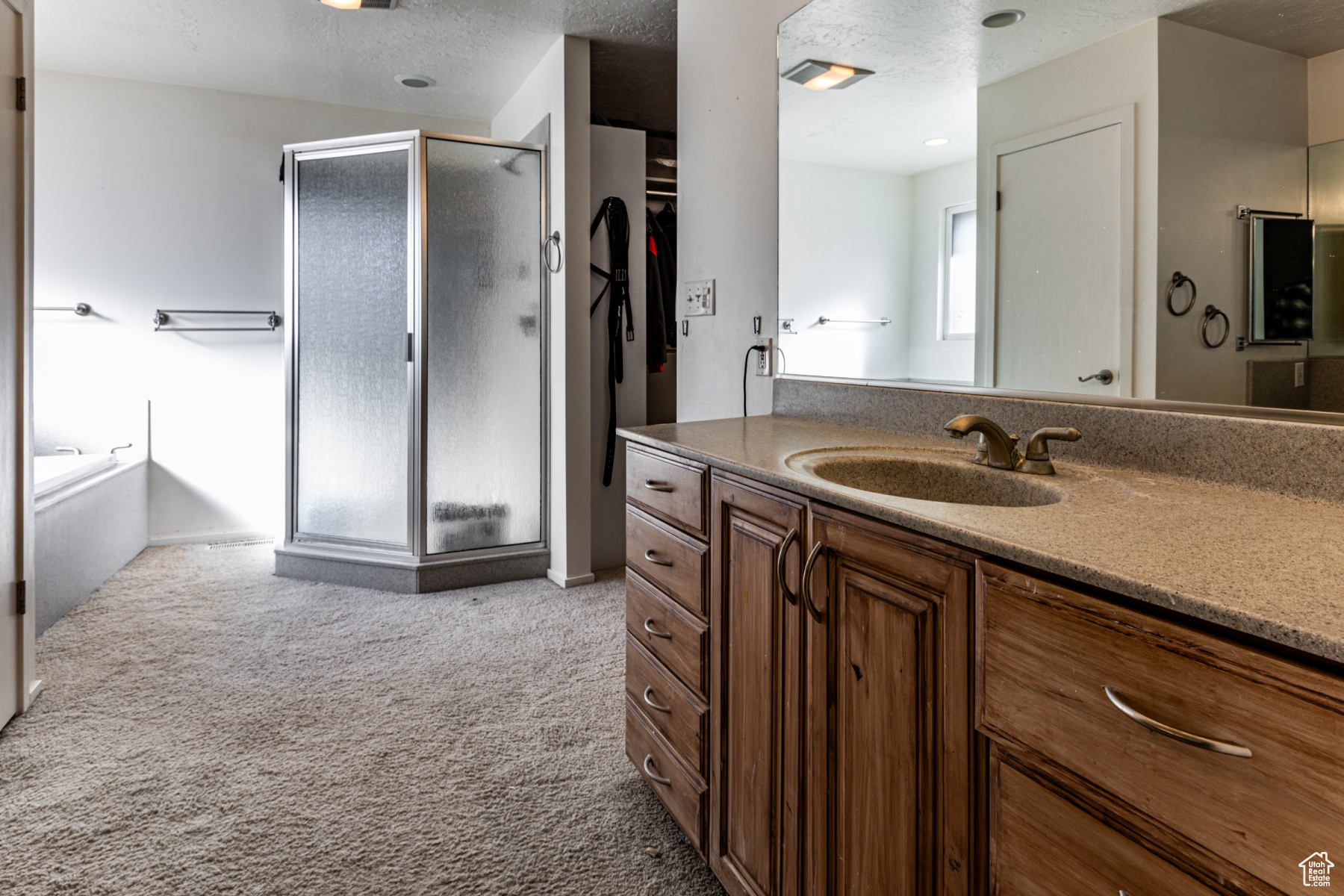 Bathroom with vanity, shower with separate bathtub, and a textured ceiling