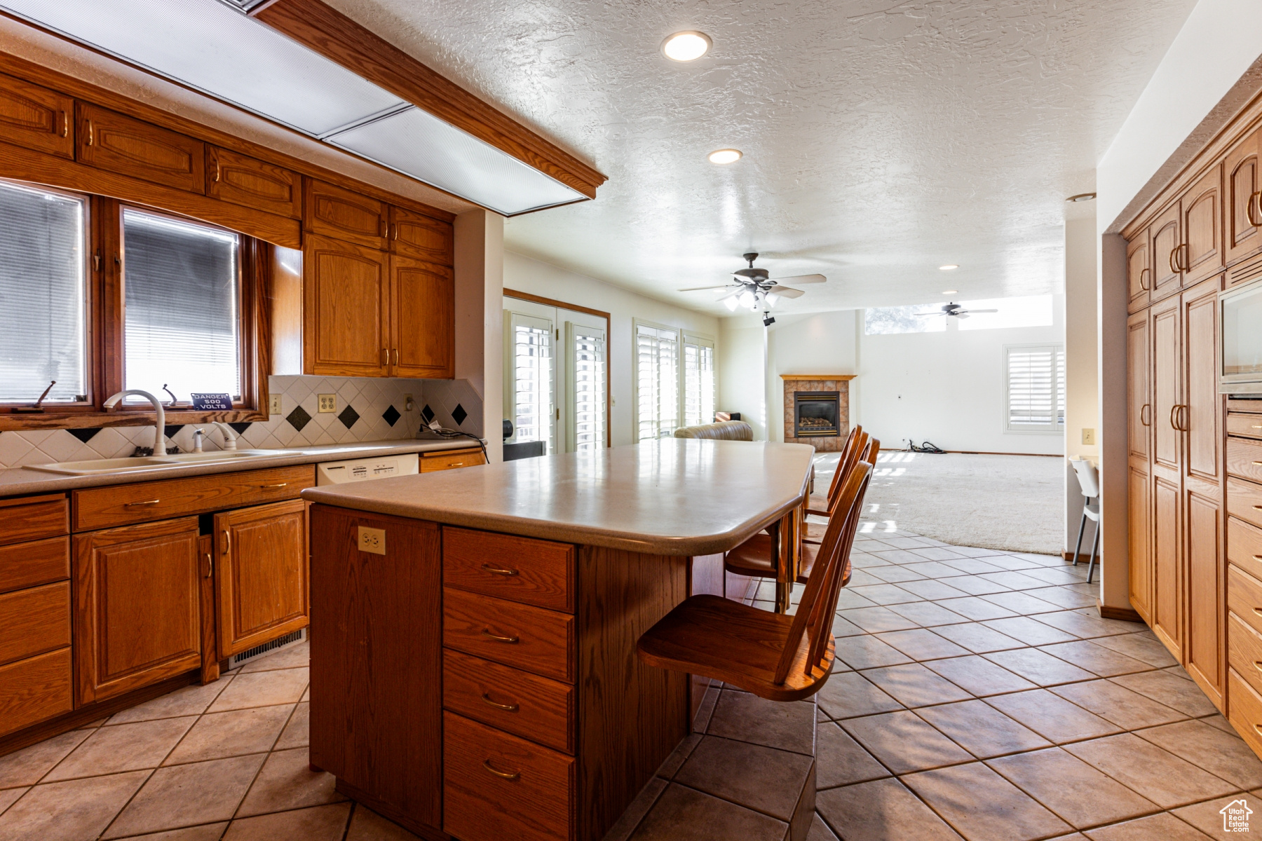 Kitchen with a kitchen island, sink, backsplash, a kitchen breakfast bar, and ceiling fan