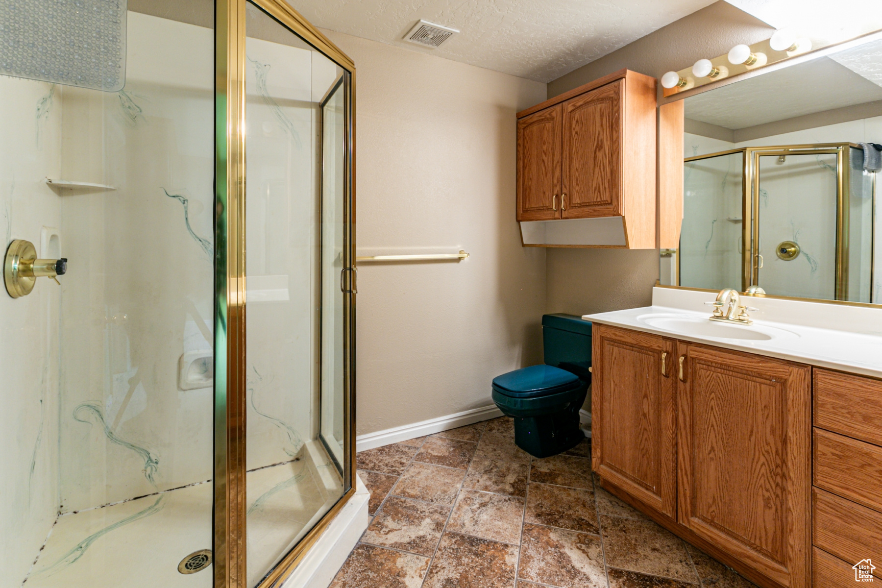 Bathroom with vanity, toilet, an enclosed shower, and a textured ceiling