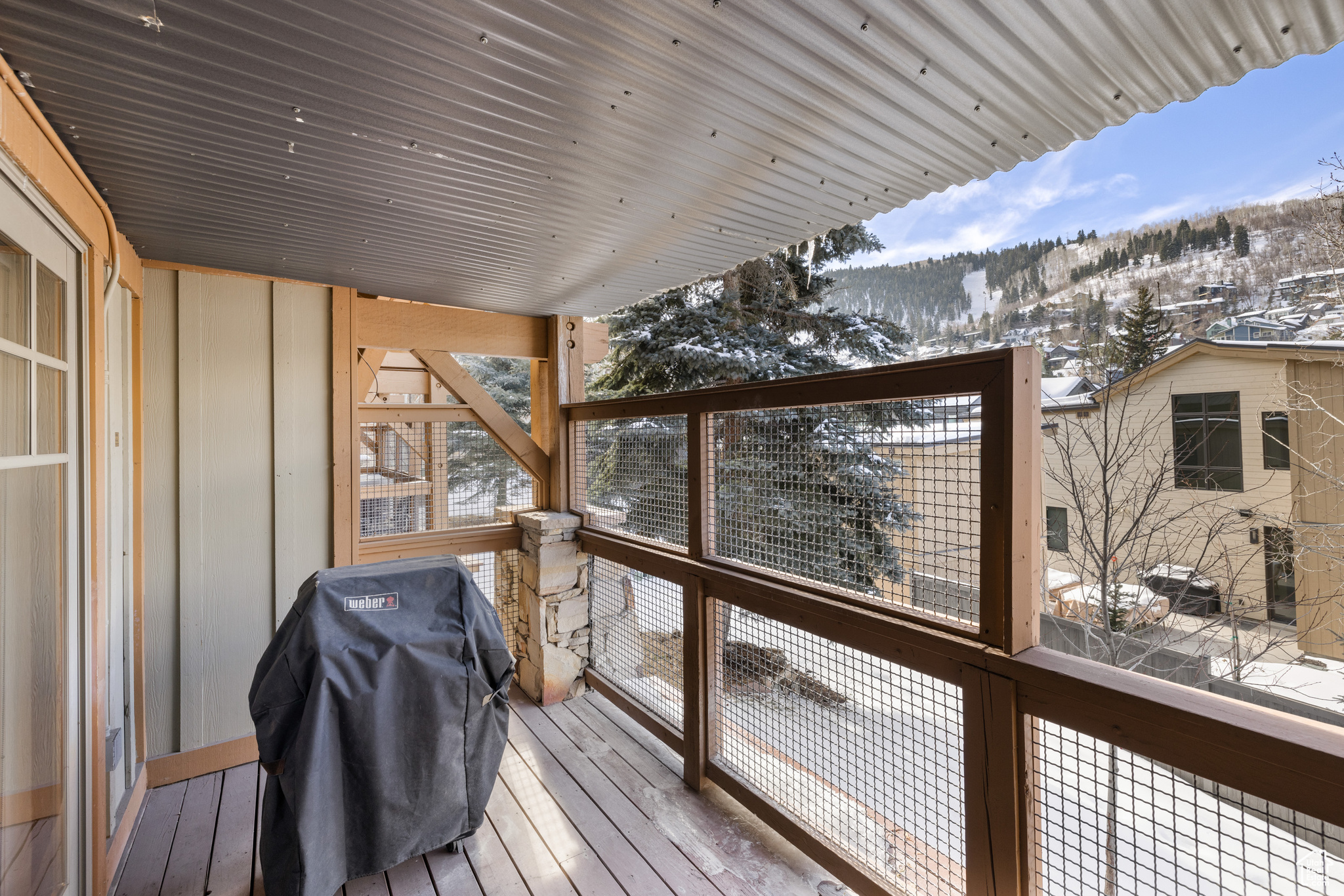 Snow covered deck with grilling area and a mountain view