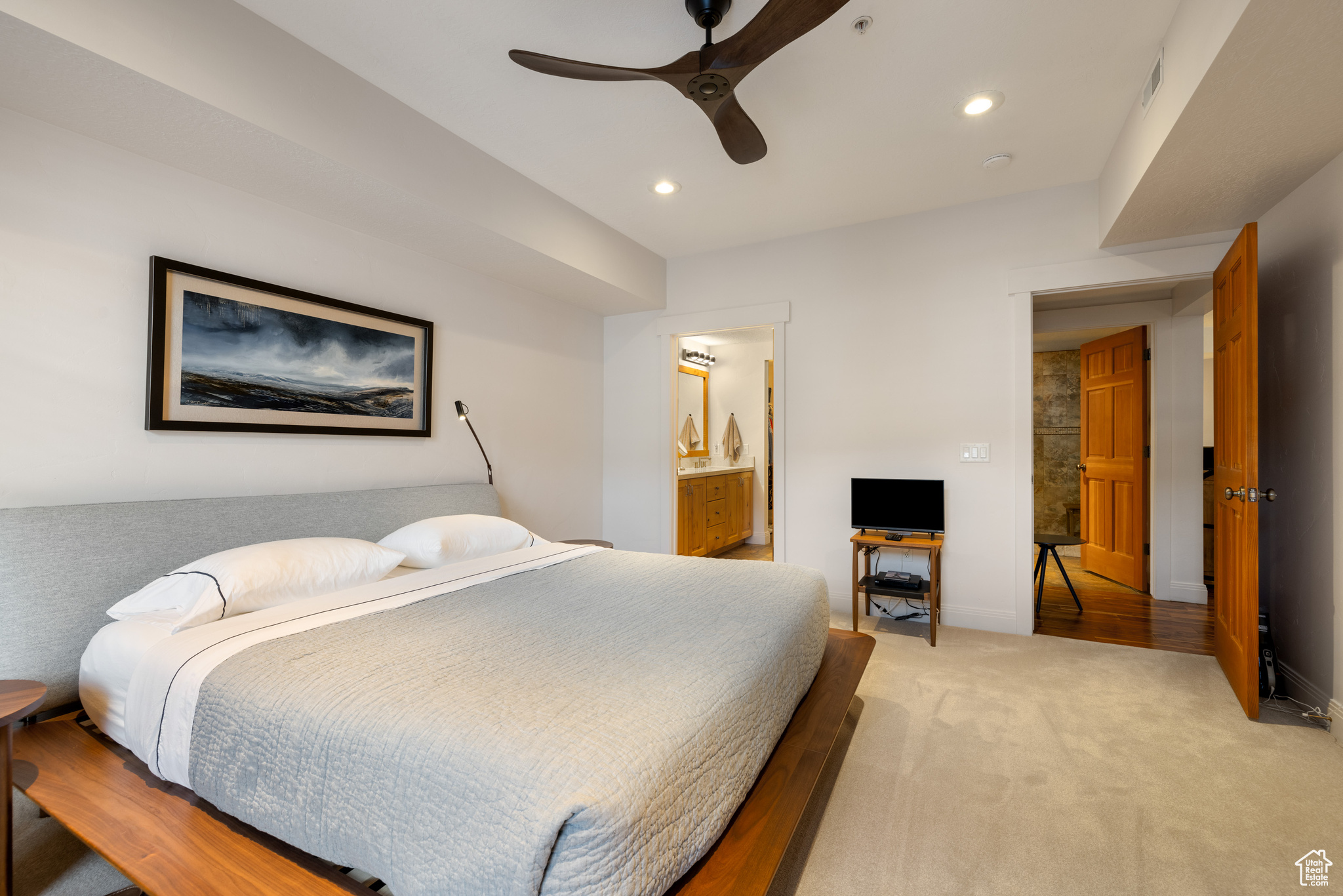 Bedroom featuring light carpet, connected bathroom, and ceiling fan