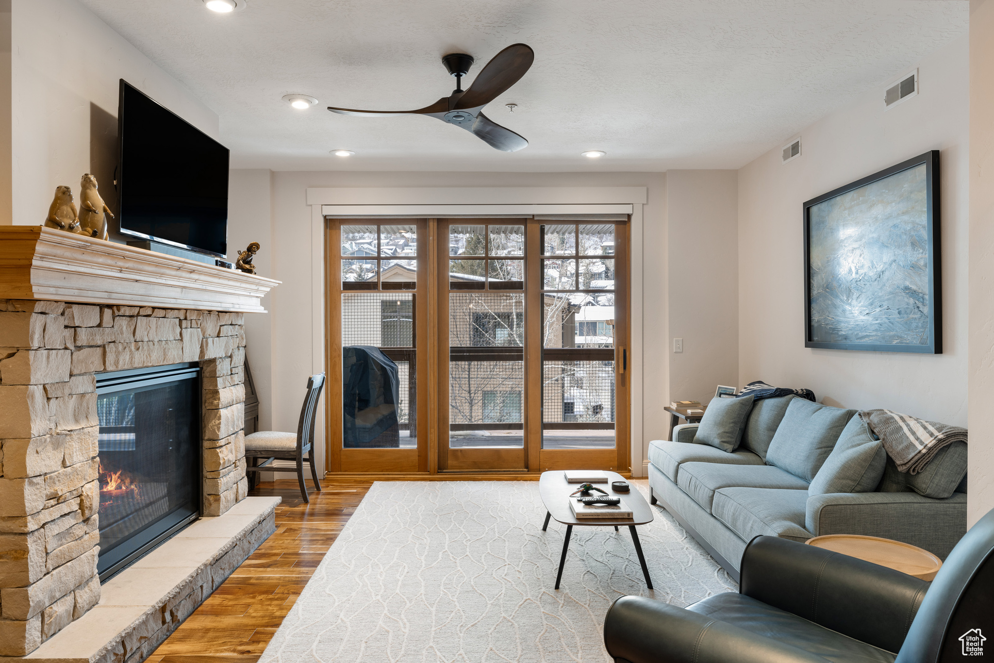 Living room with ceiling fan, a fireplace, and light hardwood / wood-style floors