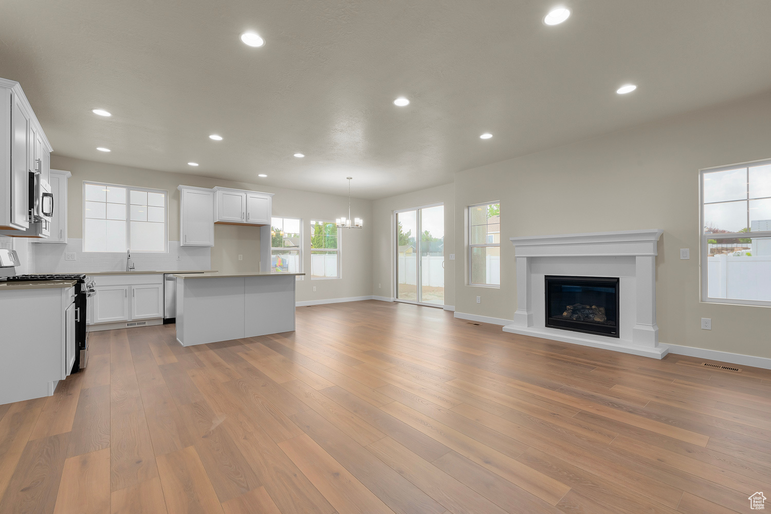 Unfurnished living room featuring an inviting chandelier, sink, and light wood-type flooring