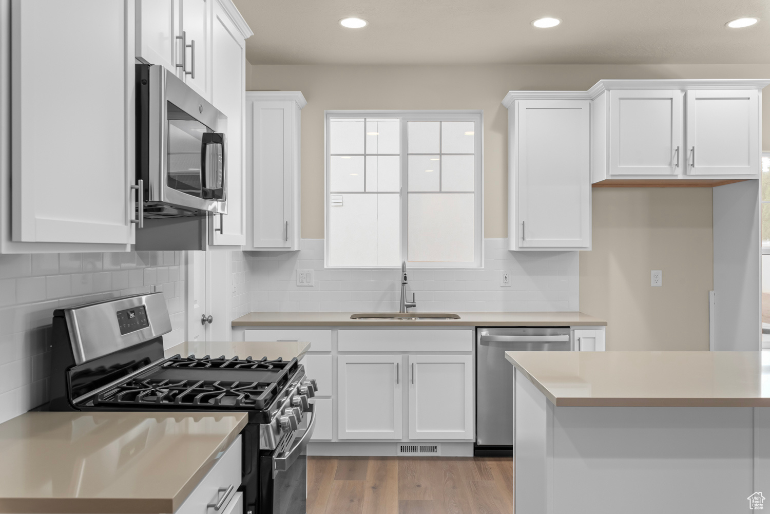 Kitchen featuring white cabinetry, sink, light hardwood / wood-style flooring, and appliances with stainless steel finishes