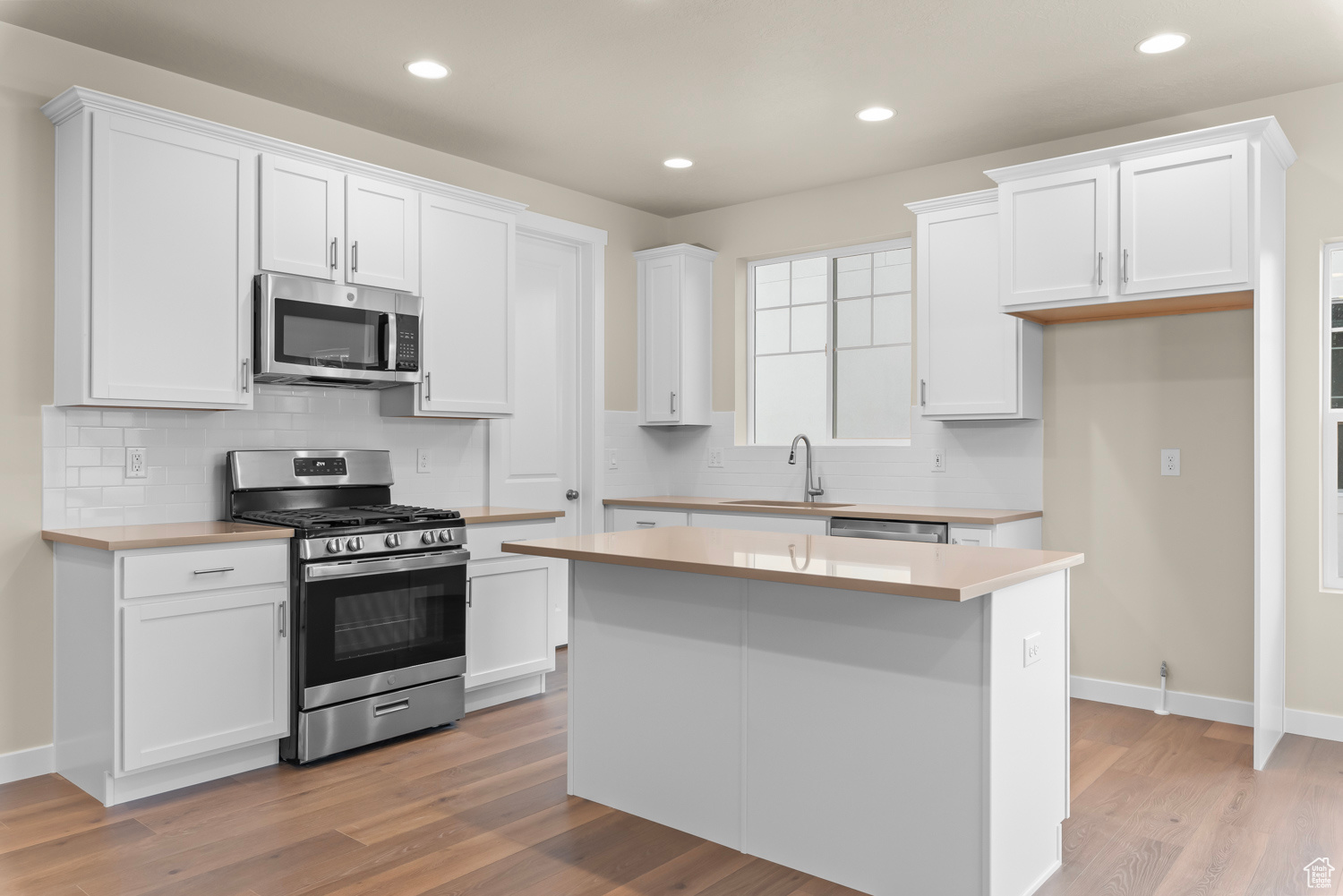 Kitchen with white cabinetry and appliances with stainless steel finishes