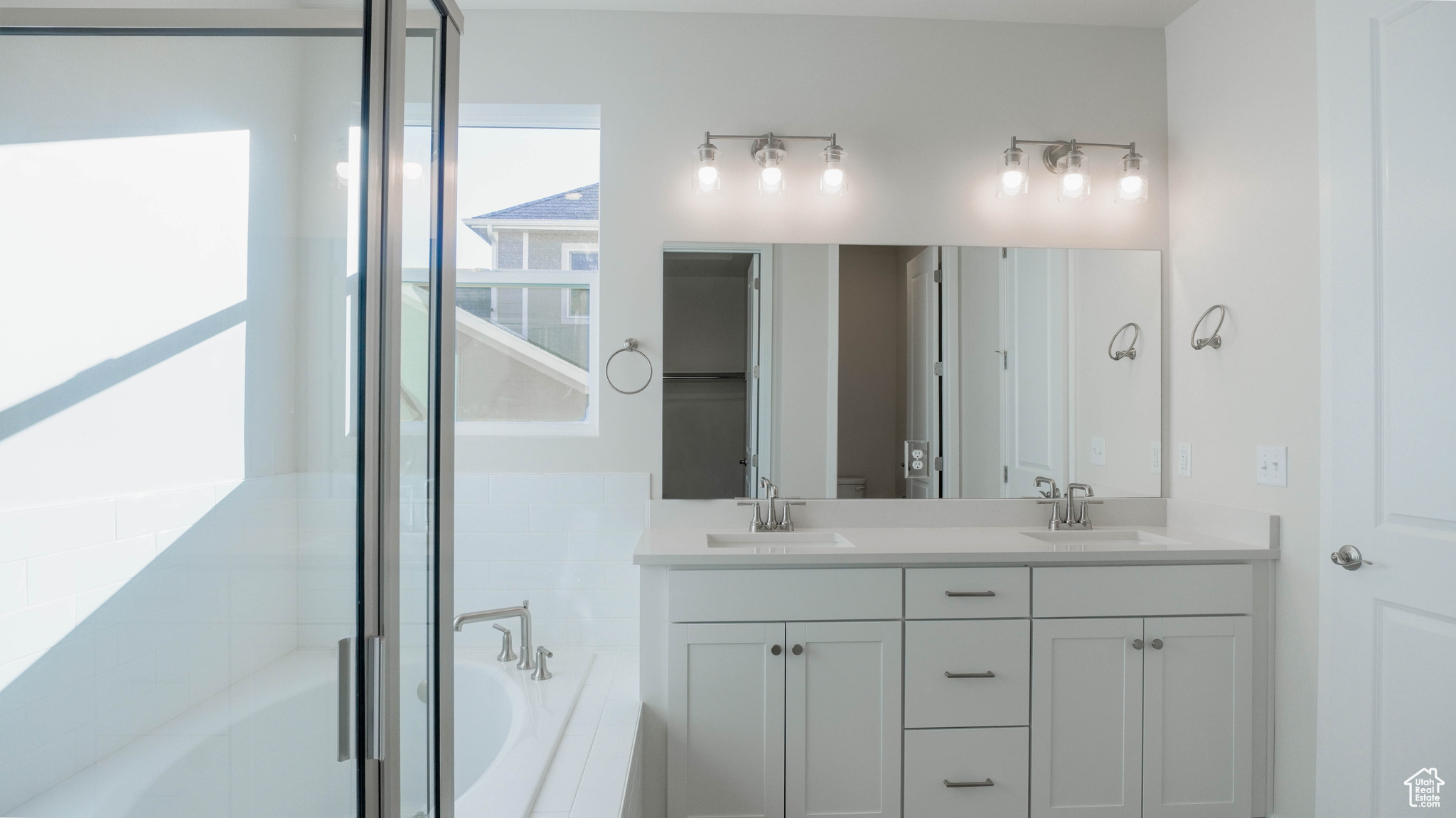 Full bath featuring a bath, double vanity, and a sink