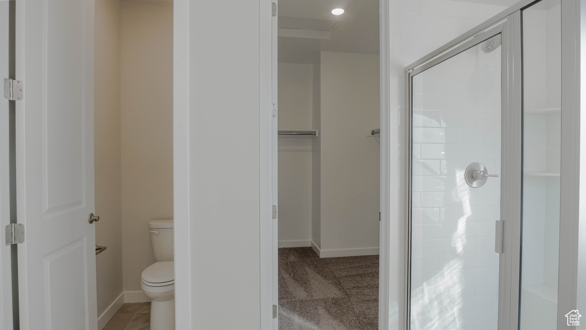 Full bath featuring a walk in closet, baseboards, toilet, and a shower stall