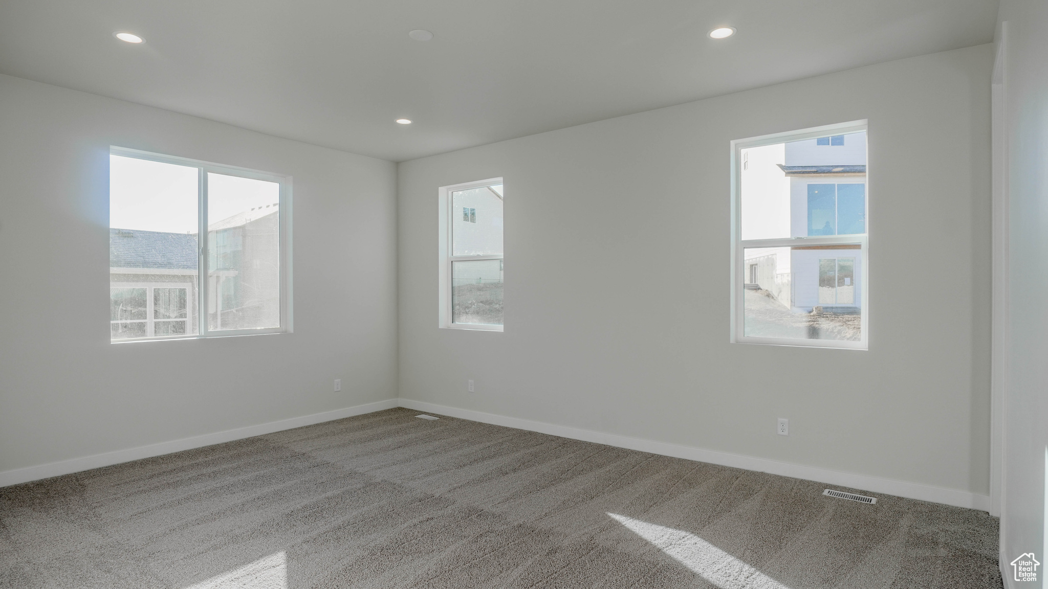 Carpeted spare room featuring a wealth of natural light, baseboards, and recessed lighting