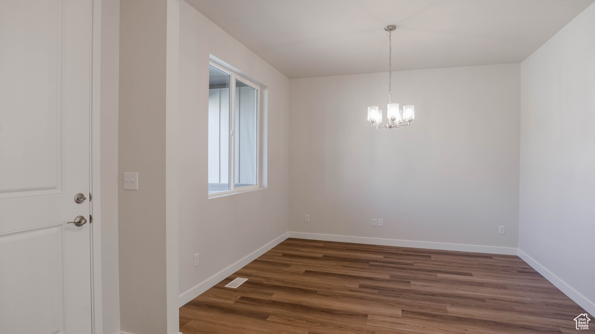 Unfurnished dining area with dark wood-type flooring, baseboards, and a chandelier