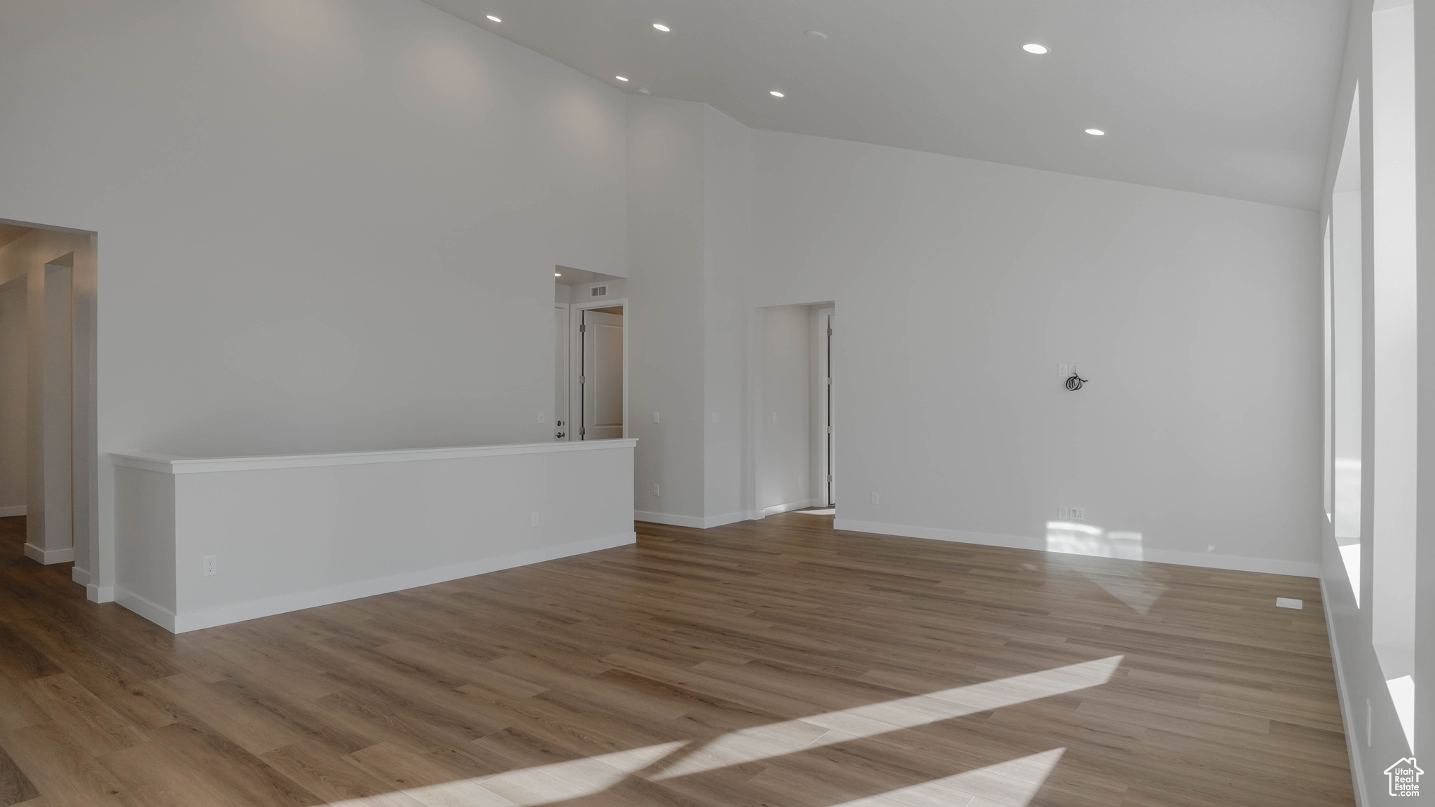 Unfurnished room with a high ceiling, recessed lighting, wood finished floors, and baseboards