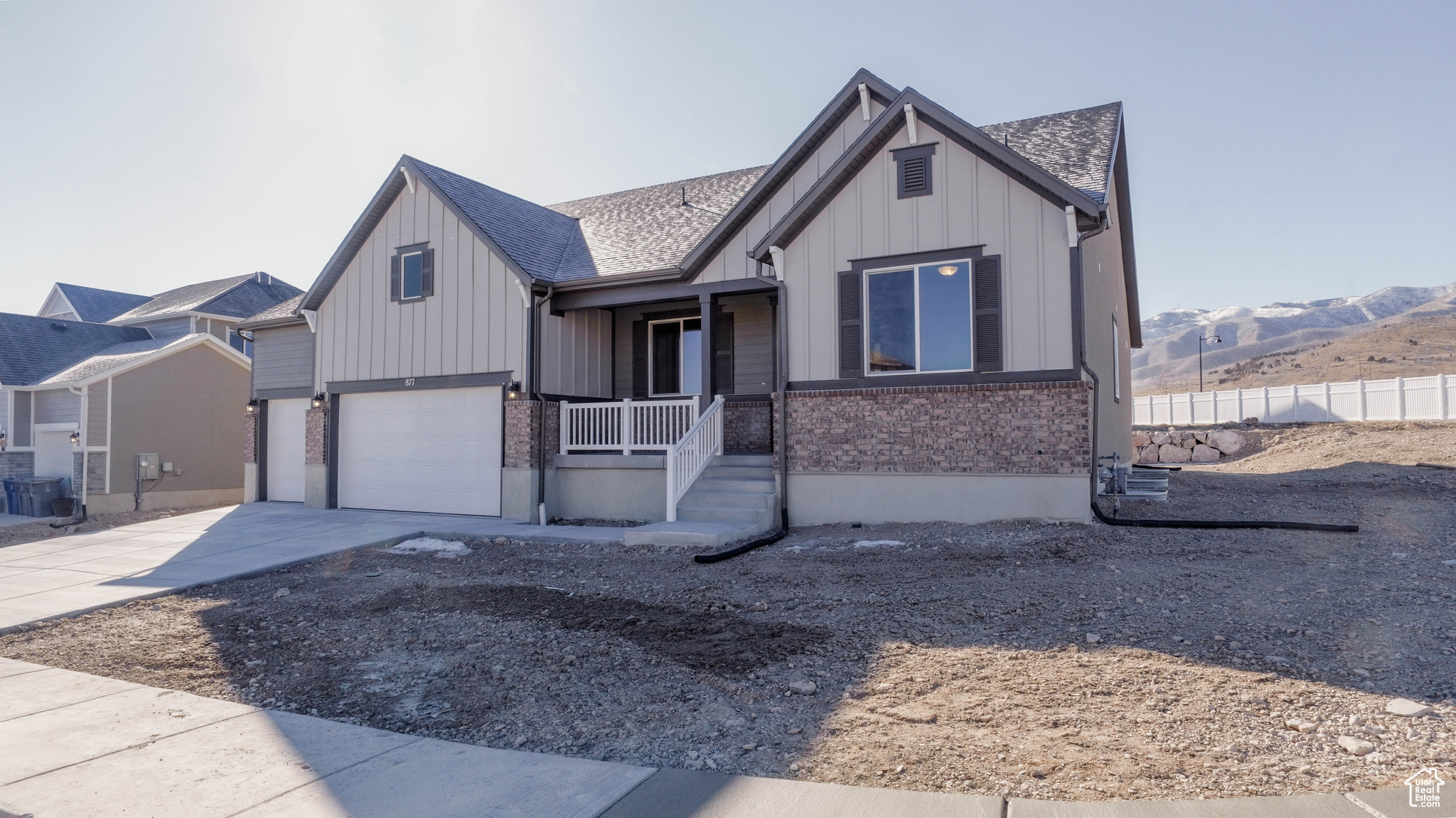 View of front facade with brick siding, board and batten siding, concrete driveway, covered porch, and an attached garage
