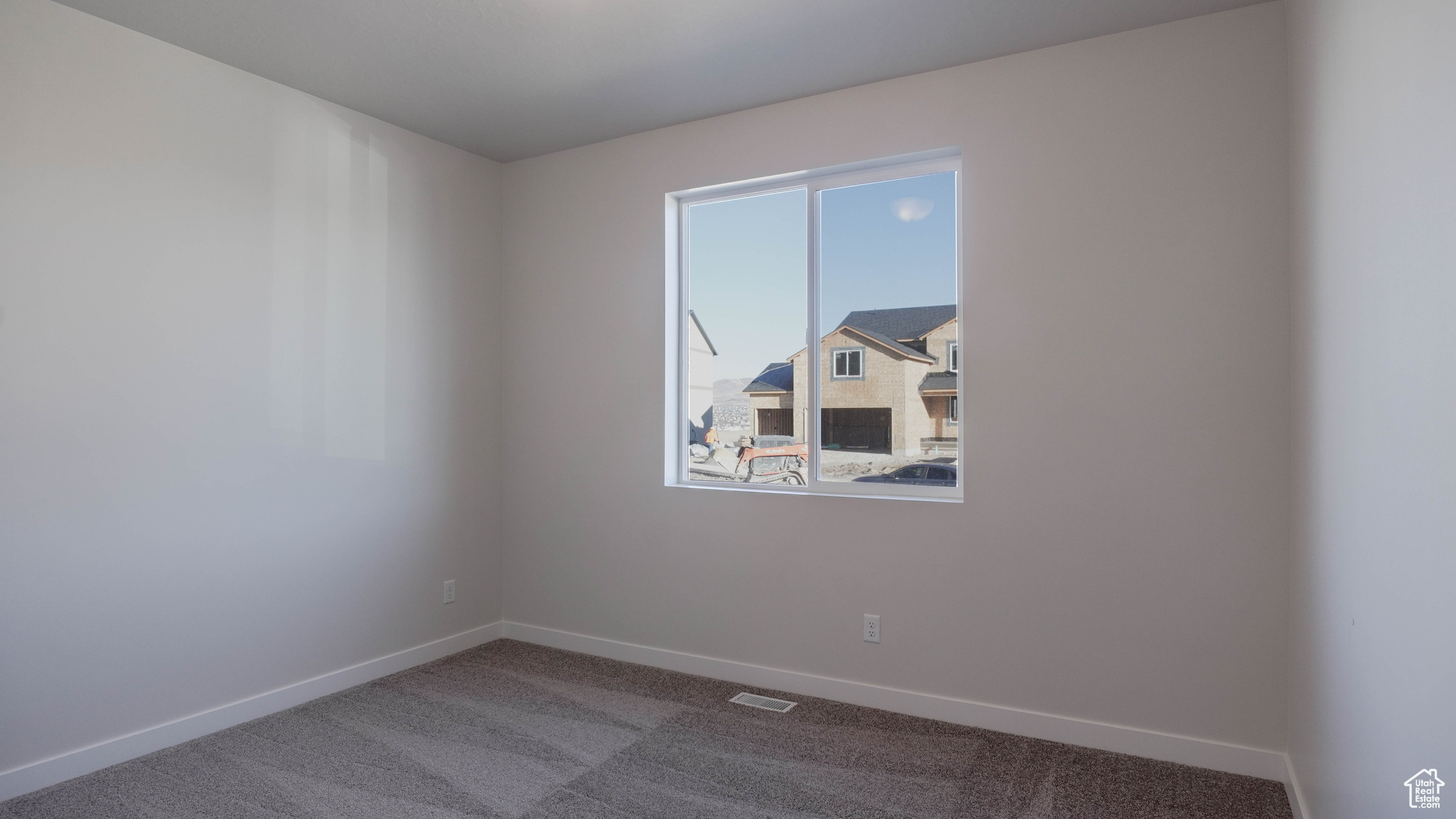 Carpeted empty room with visible vents and baseboards