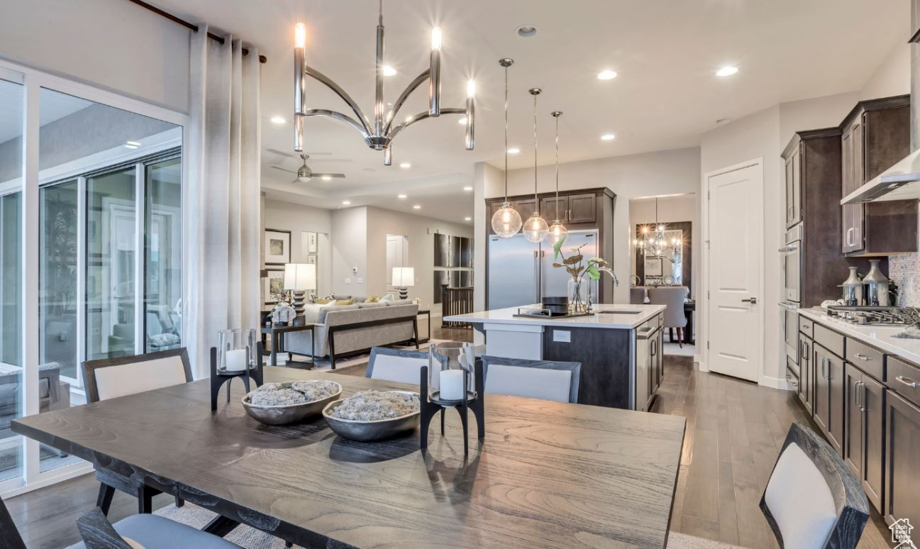 Dining room featuring sink, ceiling fan with notable chandelier, and dark wood-type flooring