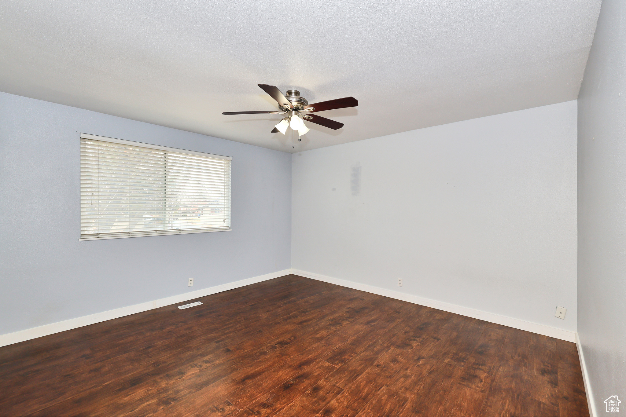 Spare room featuring ceiling fan and dark hardwood / wood-style flooring