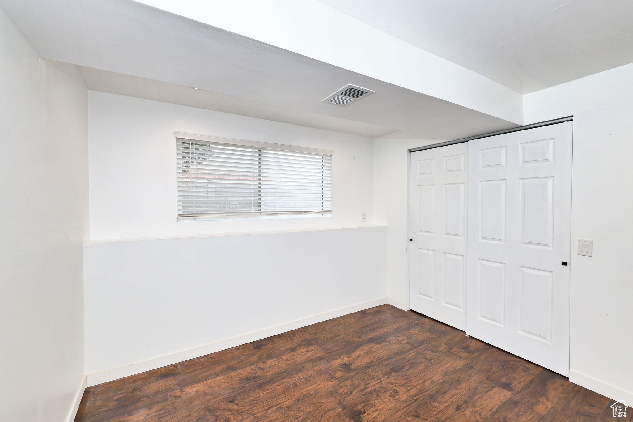 Unfurnished bedroom featuring dark hardwood / wood-style flooring and a closet