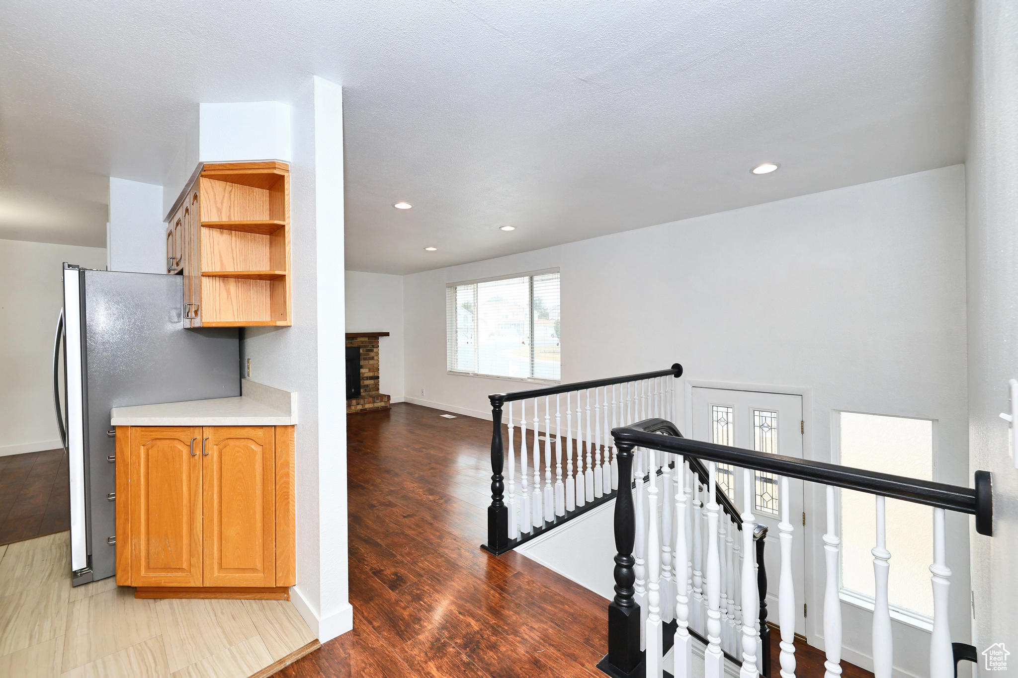 Kitchen featuring stainless steel fridge, hardwood / wood-style floors, and a brick fireplace