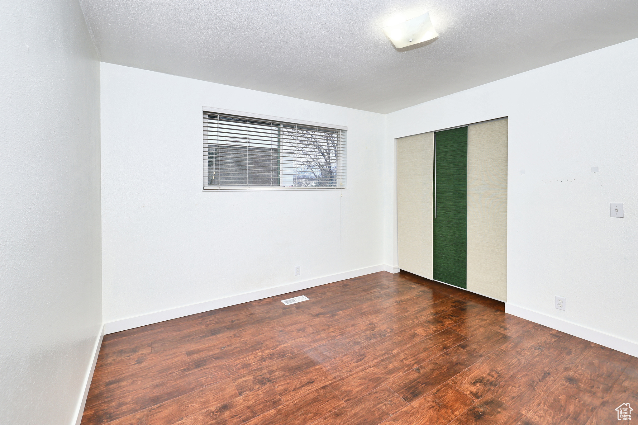 Unfurnished room featuring dark hardwood / wood-style flooring and a textured ceiling