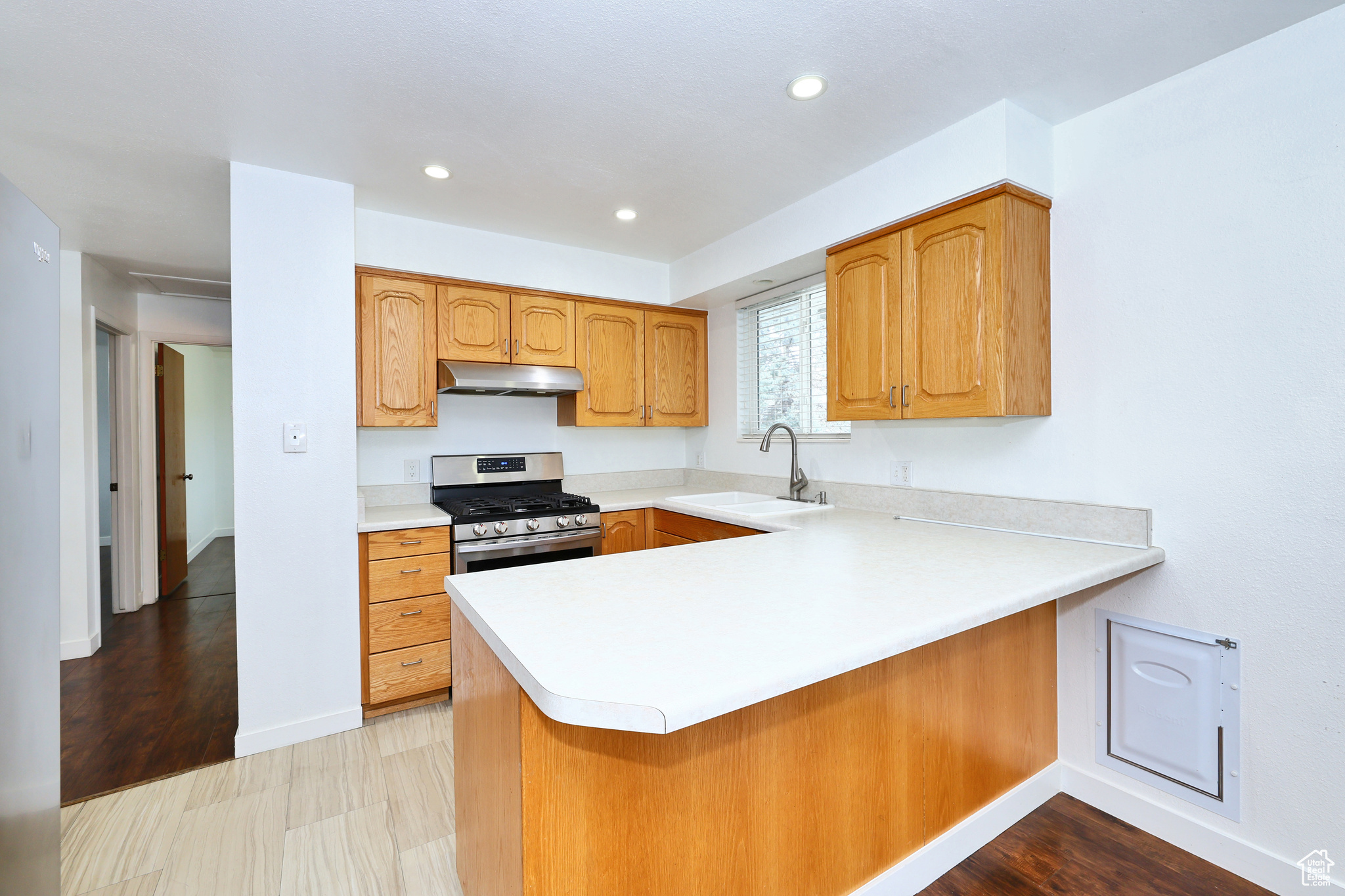 Kitchen with stainless steel gas range, sink, and kitchen peninsula