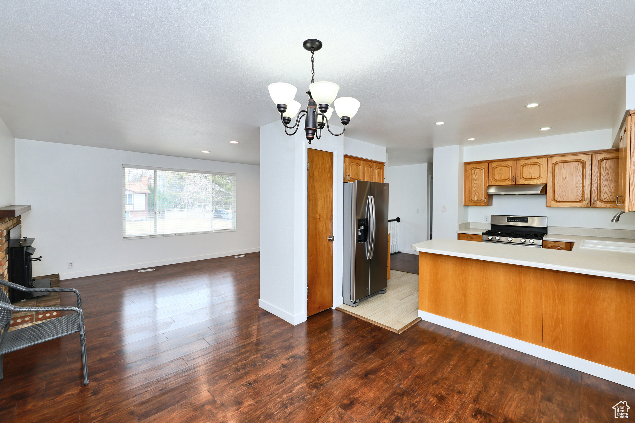 Kitchen featuring sink, decorative light fixtures, dark wood-type flooring, and appliances with stainless steel finishes