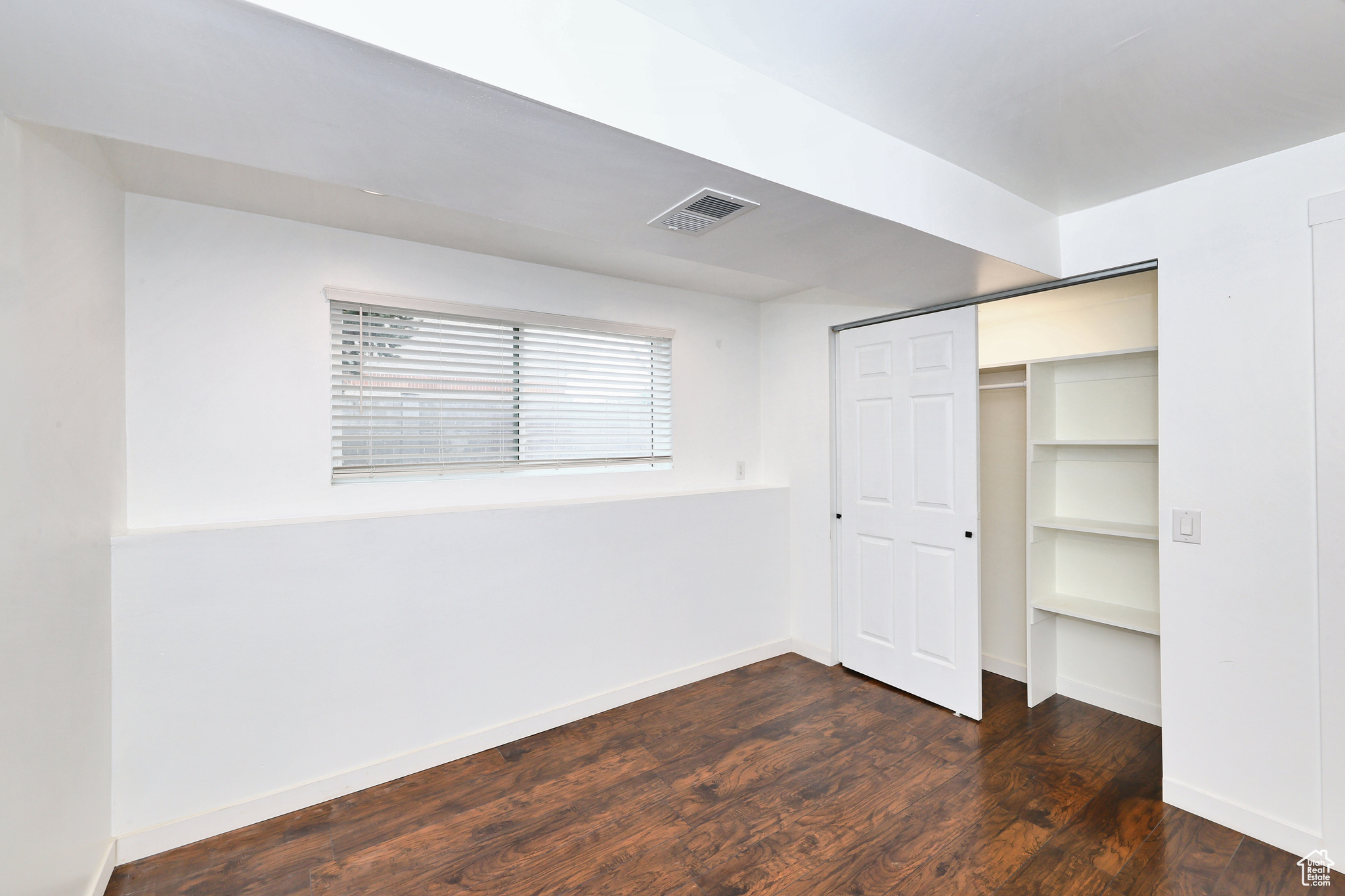 Unfurnished bedroom featuring dark hardwood / wood-style flooring and a closet