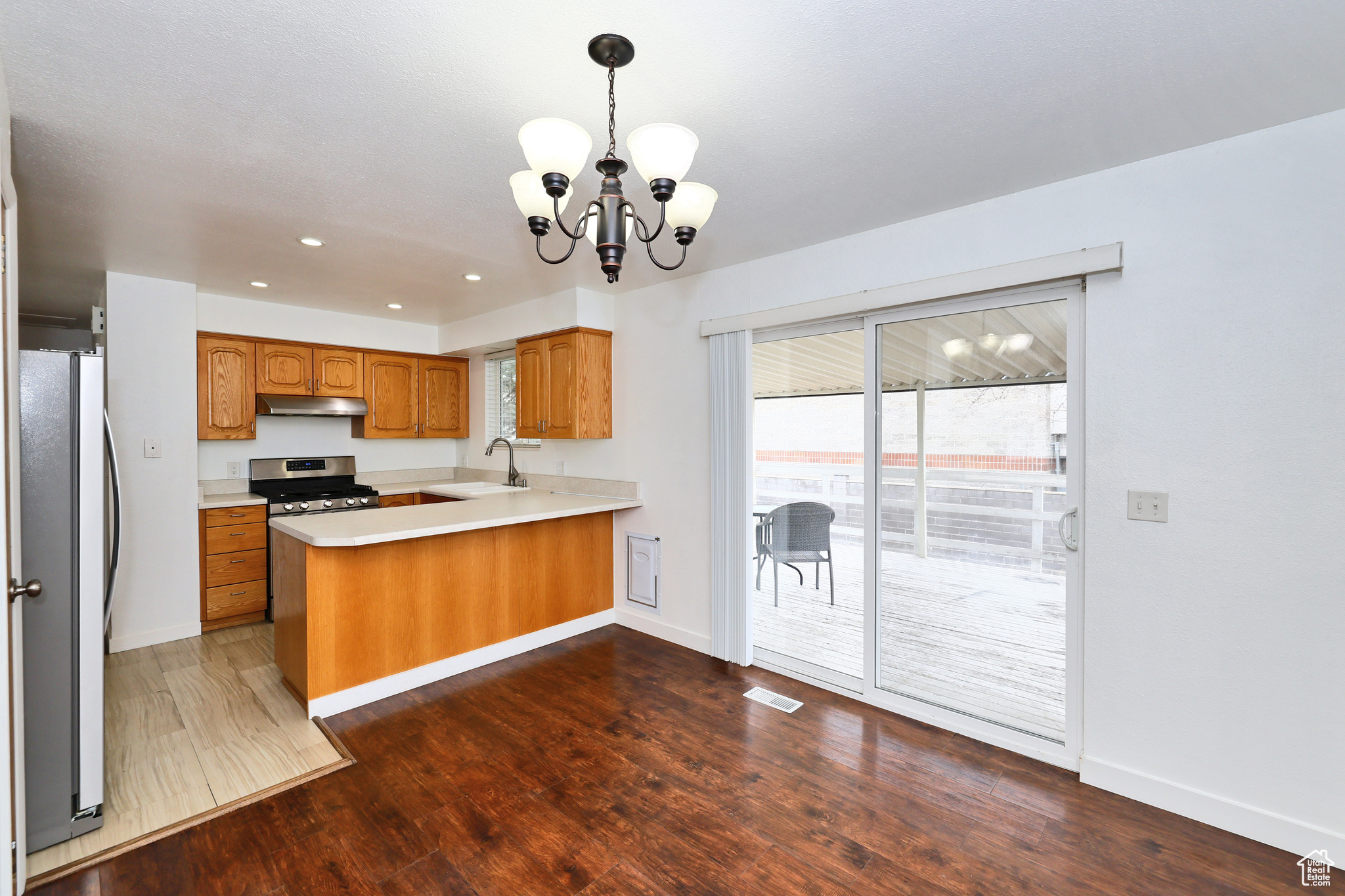 Kitchen featuring pendant lighting, sink, kitchen peninsula, stainless steel appliances, and dark wood-type flooring