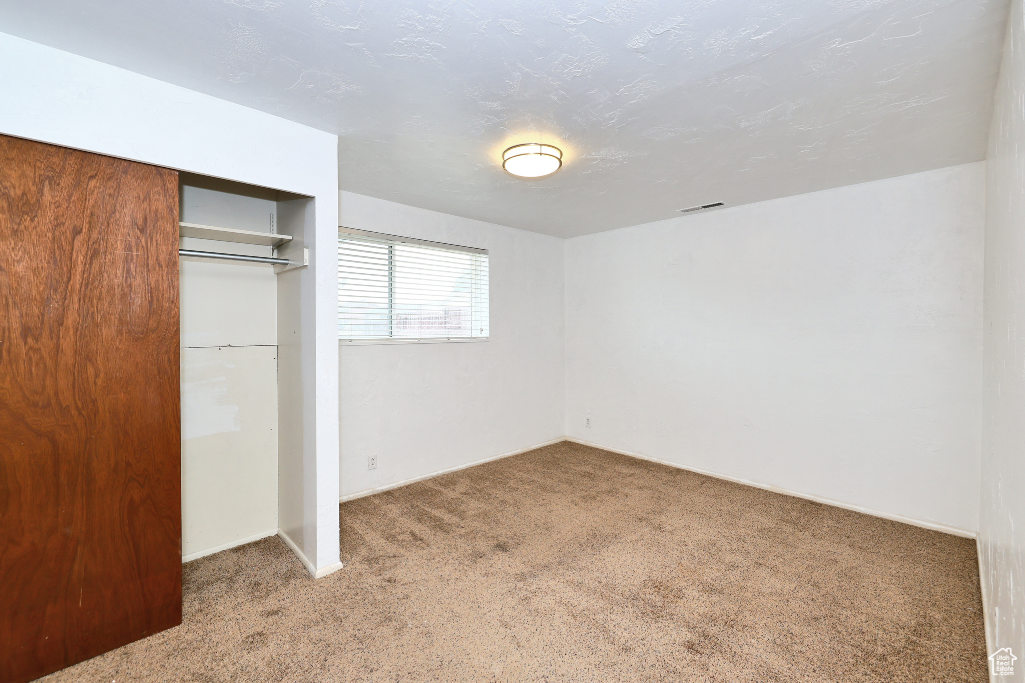 Unfurnished bedroom with a closet, carpet, and a textured ceiling