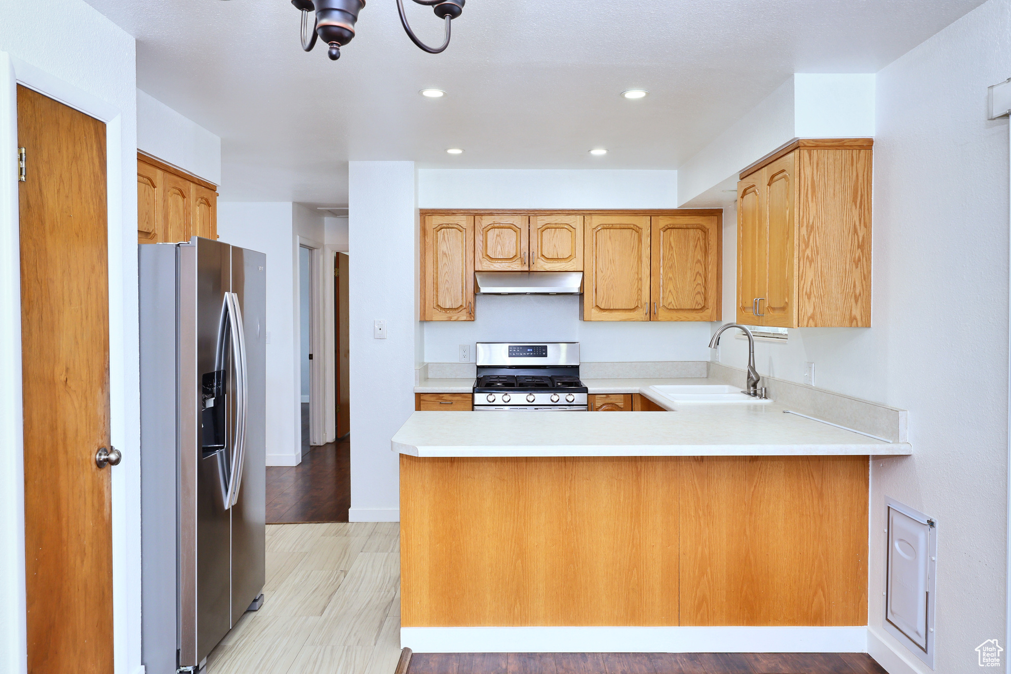 Kitchen with stainless steel appliances, kitchen peninsula, sink, and light wood-type flooring