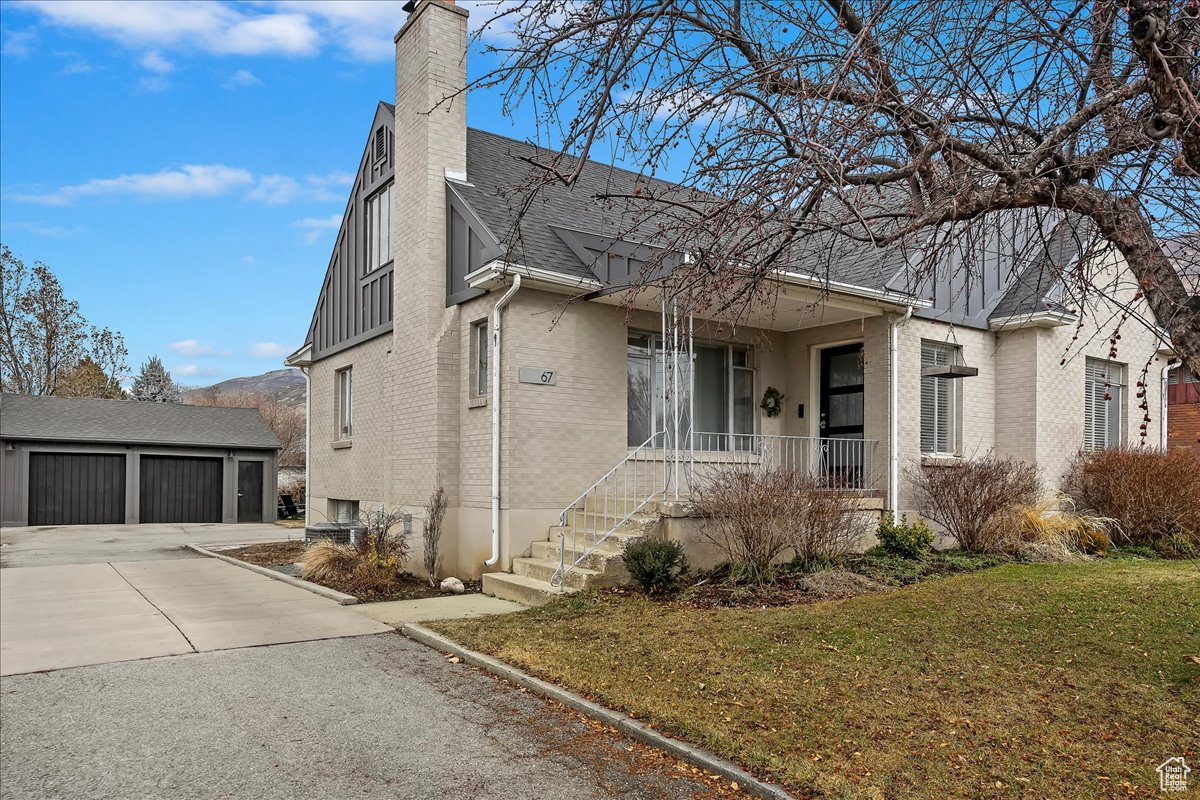 View of front of property with an outbuilding, a garage, a front yard, and covered porch