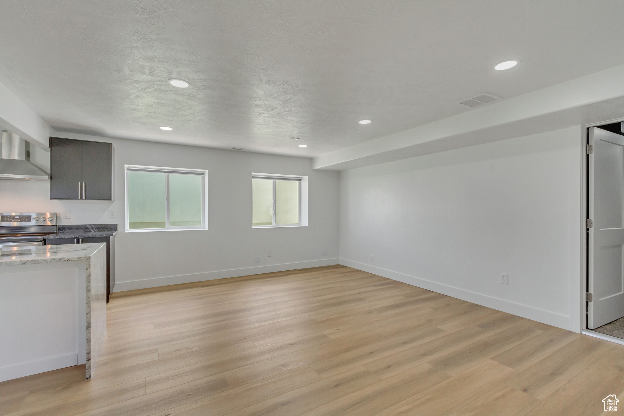 Interior space with gray cabinetry, light stone counters, a textured ceiling, light hardwood / wood-style flooring, and stainless steel electric stove