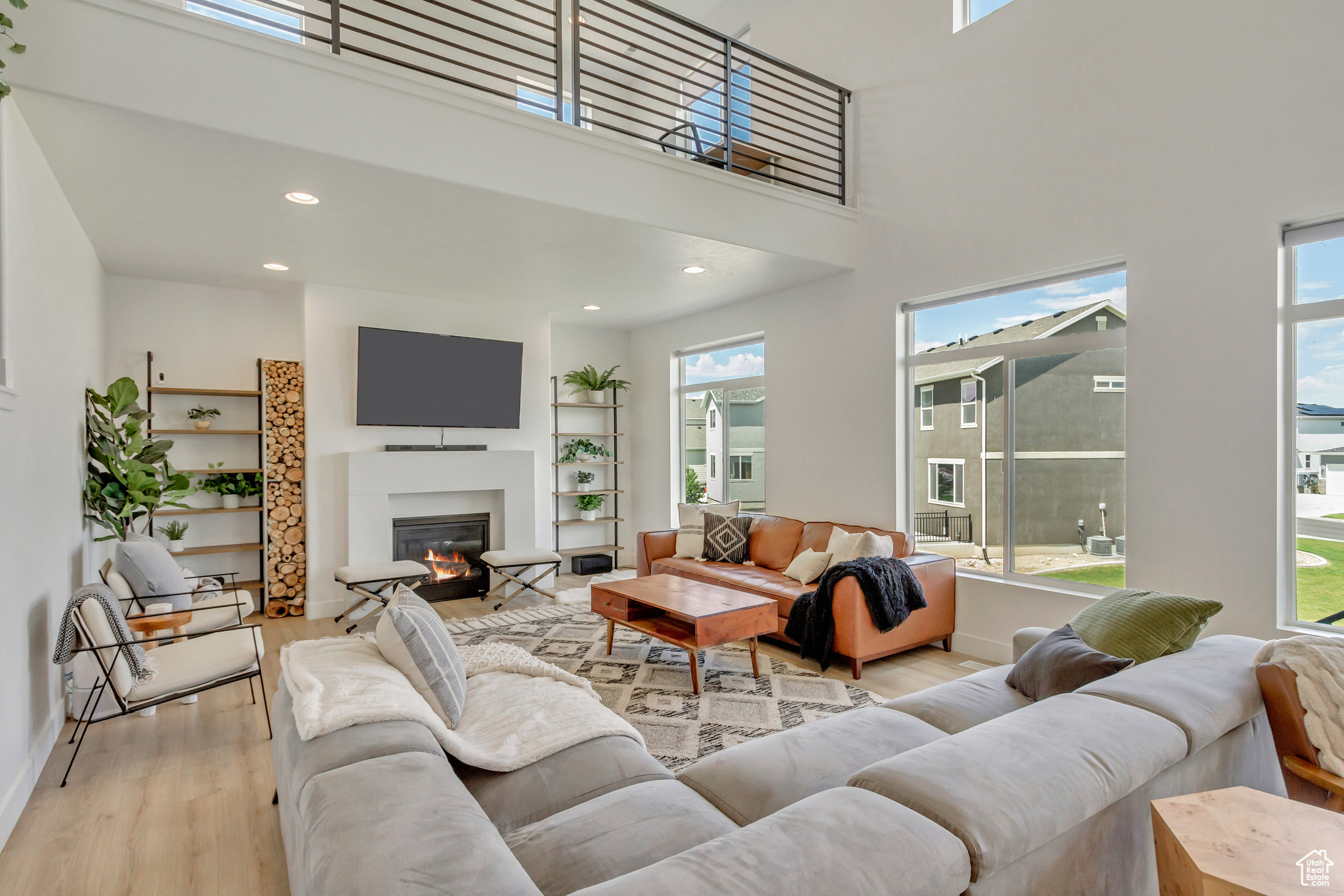 Living room with a high ceiling, light hardwood / wood-style flooring, and a wealth of natural light