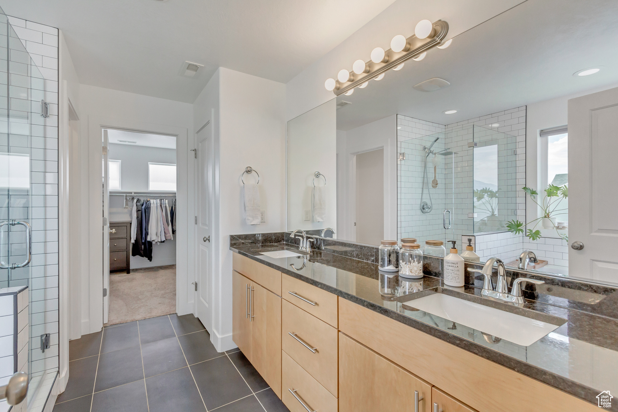 Bathroom with tasteful backsplash, vanity, tile patterned floors, and walk in shower