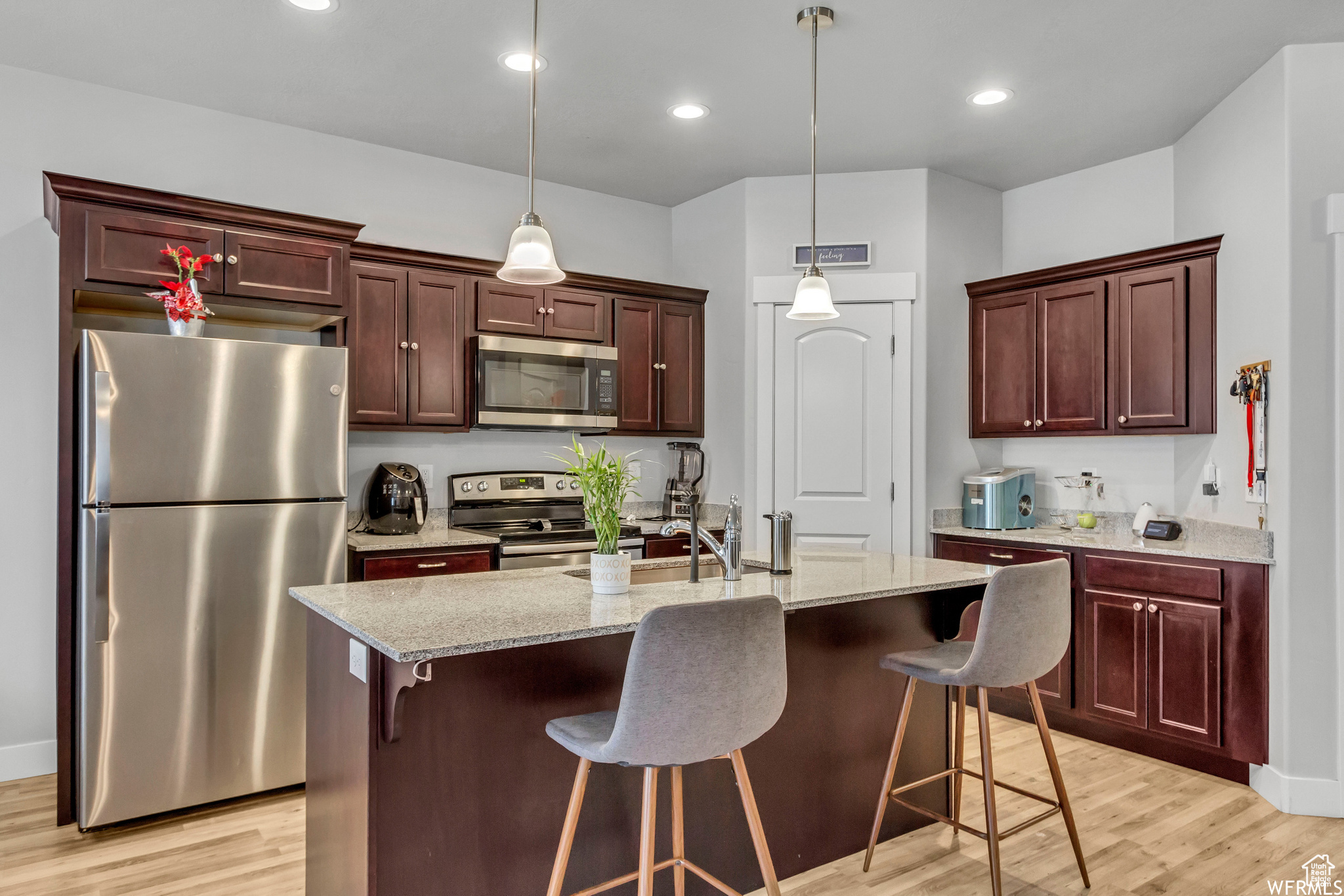 Kitchen with stainless steel appliances, an island with sink, light stone countertops, and a kitchen breakfast bar