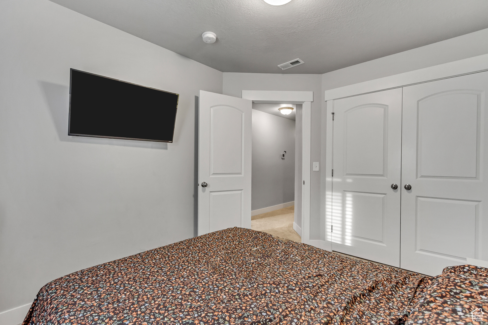 Unfurnished bedroom featuring light colored carpet, a textured ceiling, and a closet