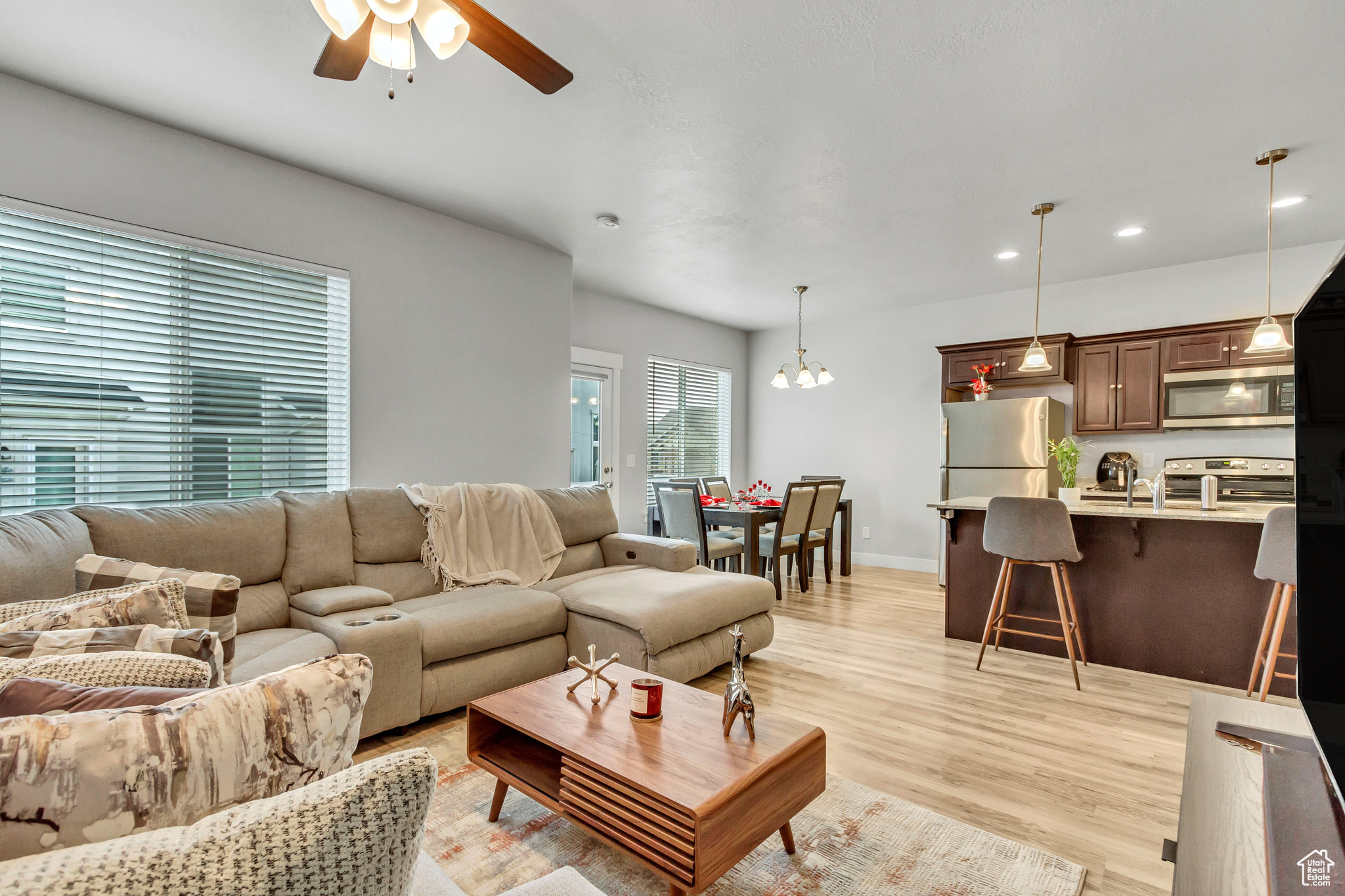 Living room with sink, ceiling fan with notable chandelier, and light wood-type flooring