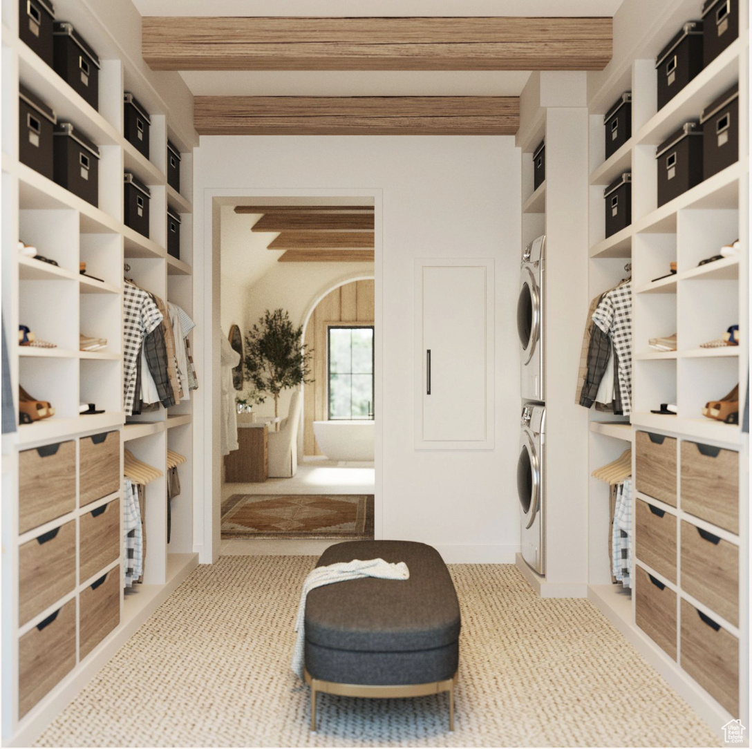 Primary Closet featuring stacked washer / drying machine and light colored carpet