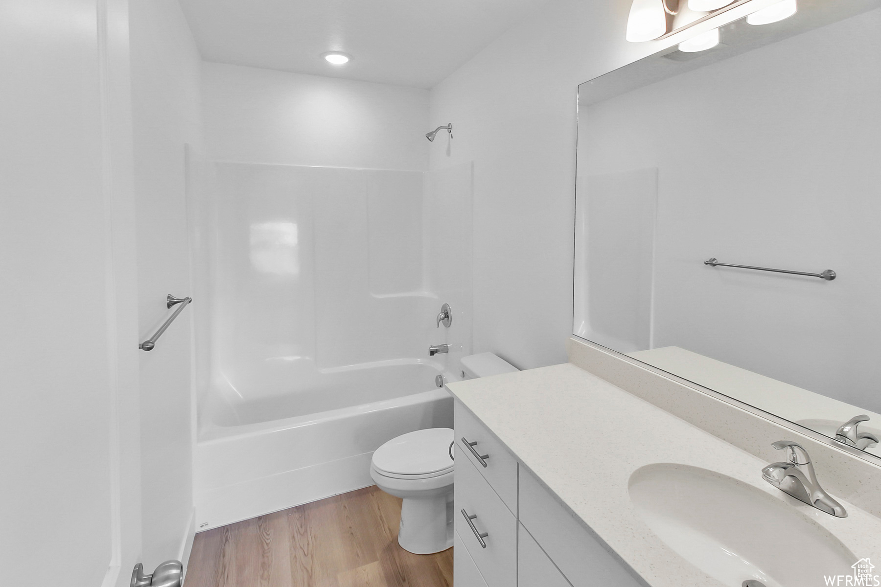 Full bathroom with vanity, hardwood / wood-style floors, tub / shower combination, and toilet