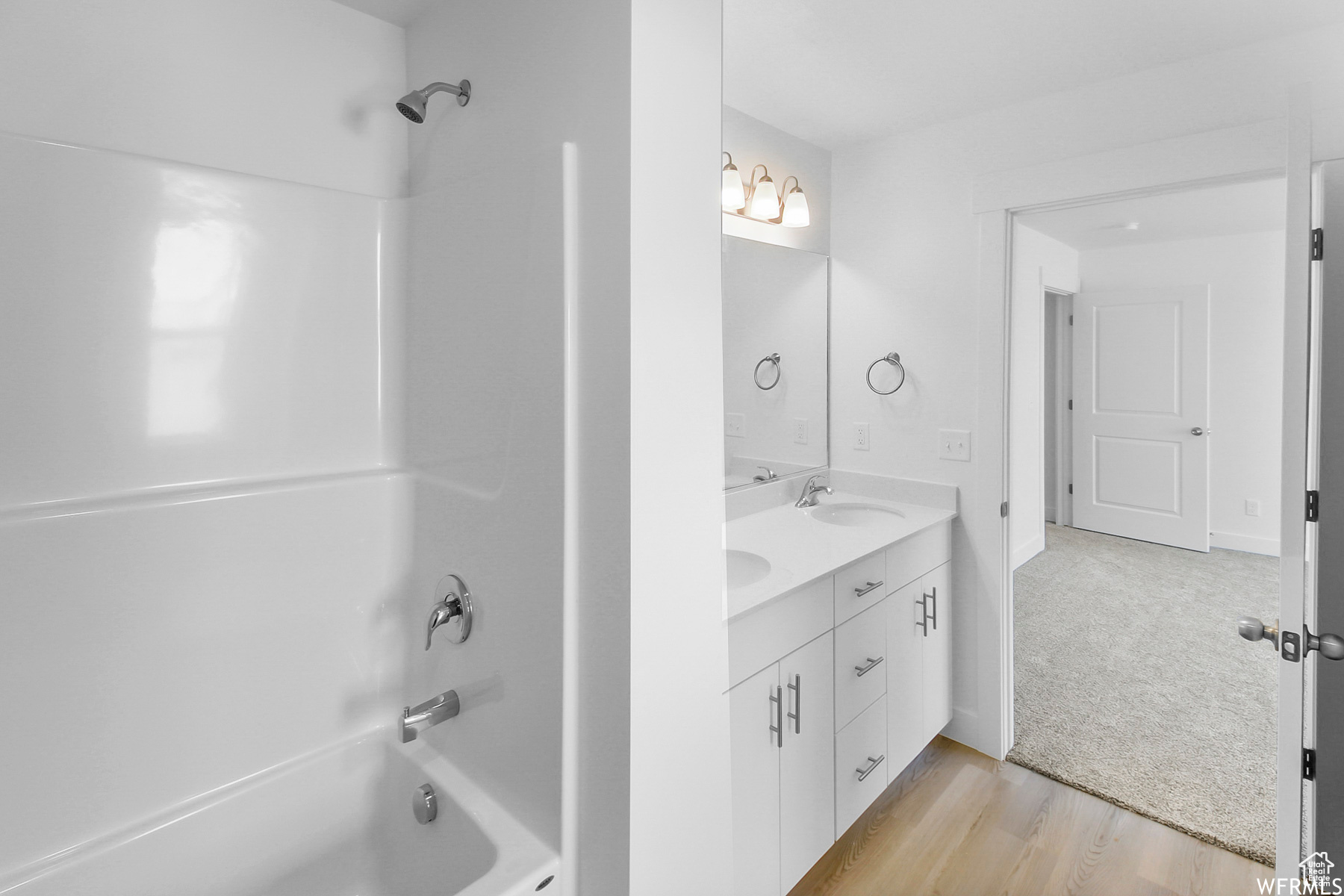 Master bathroom featuring a double sink vanity, LVP wood-style floors, and bathtub/ shower combination