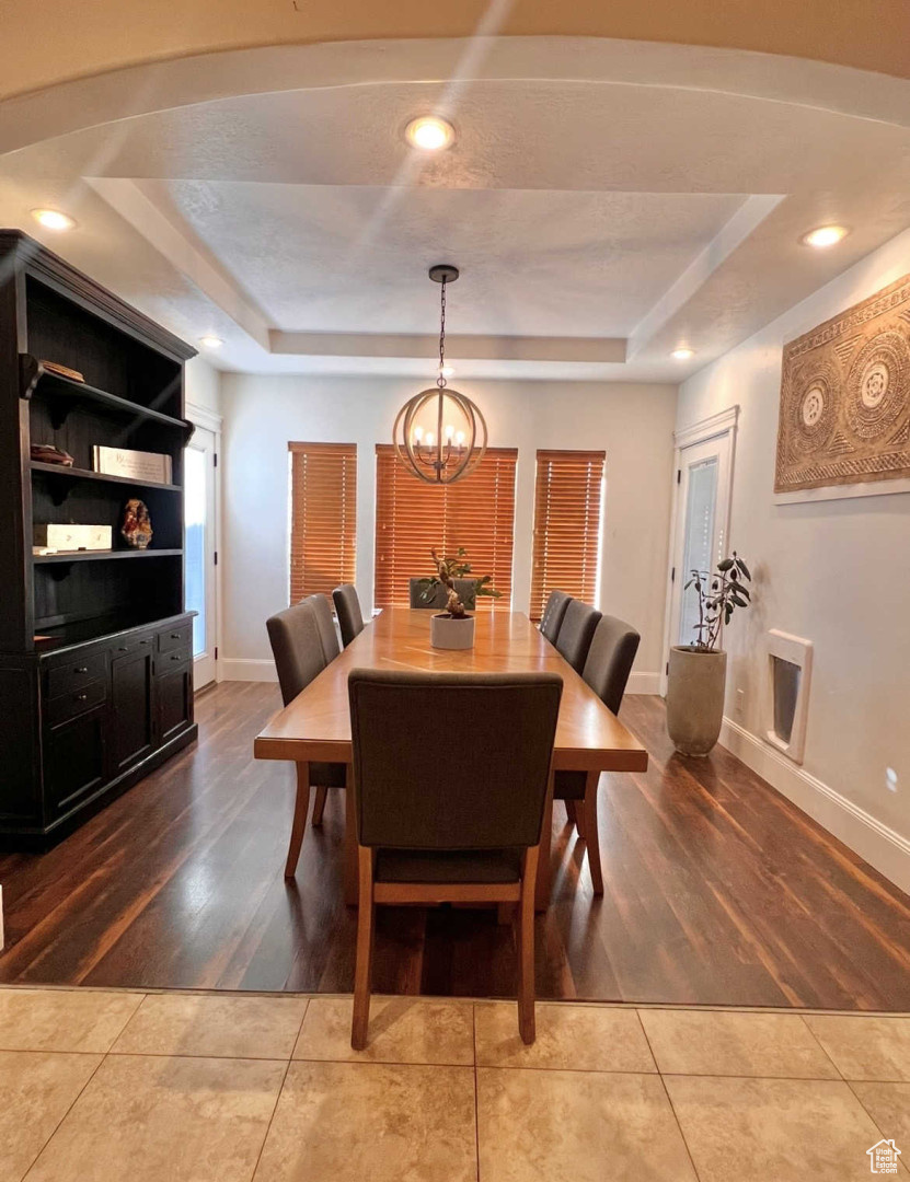 Dining area featuring tile patterned flooring, a tray ceiling, and an inviting chandelier