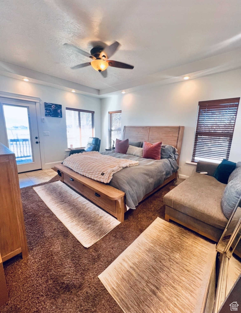 Bedroom with carpet flooring, a textured ceiling, access to exterior, and ceiling fan