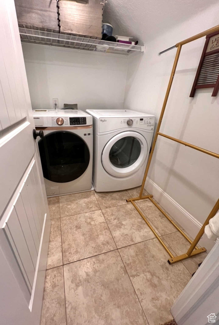 Washroom with washer and dryer and light tile patterned floors