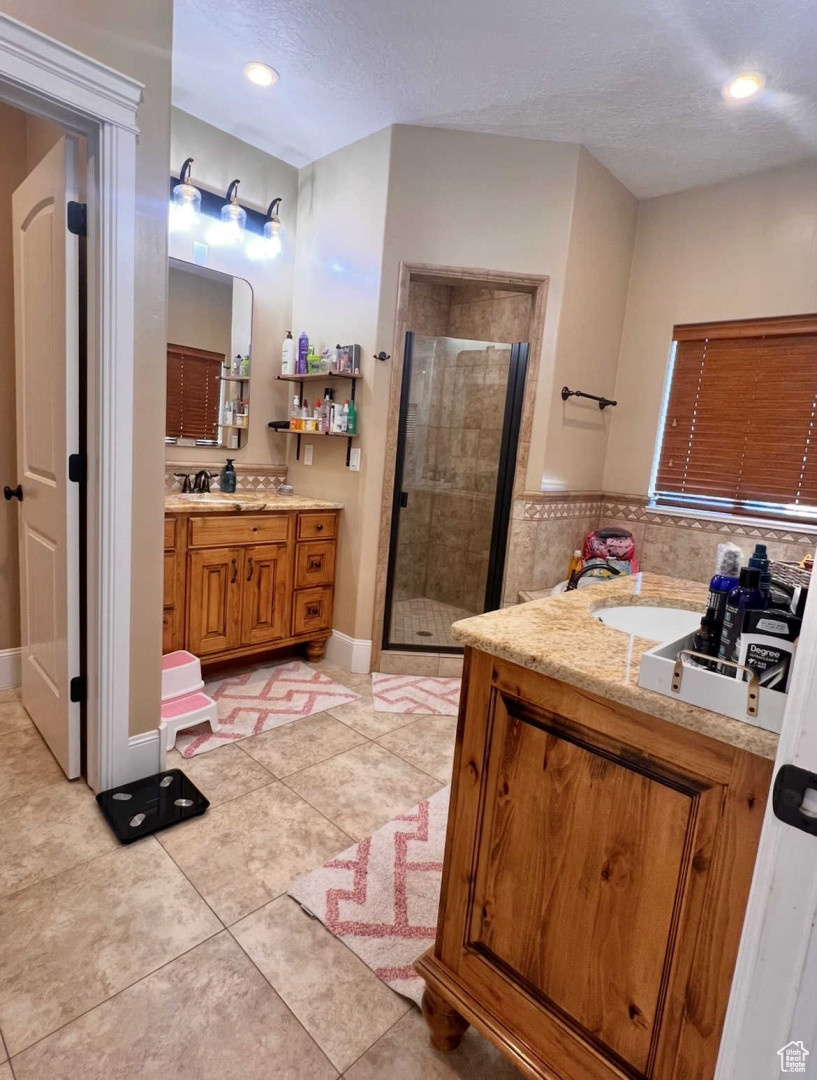 Bathroom featuring walk in shower, vanity, tile patterned flooring, and a textured ceiling